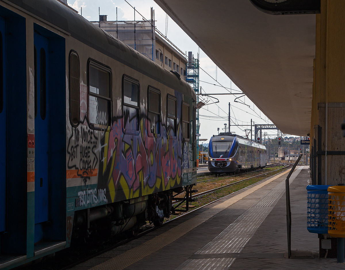 Bahnhof Syrakus (Stazione di Siracusa) am 19.07.2022: Bald wären wir in den (von dieser Seite beschmierten) Aln 668 3032 eingestiegen der von hier als R 12946 nach Augusta fährt, was ein Teil des Weges nach unserem Ziel Catania ist. Dann kam der Minuetto ME eingefahren und die Ansage das der Zug als R 5518 nach Bicocca über Catania fährt. Also wieder rüber auf Gleis 1. Wir hatten ihn einfach nicht am Schirm, weil wir das Zugziel Bicocca nicht kannten. Der Zuglauf ist auch sehr ungewöhnlich, wie folgt: Siracusa 16:01 - Augusta 16:21 - Lentini 16:43 - Bicocca (ohne Halt) - Catania Aeroporto Fontanarossa 17:00 - Catania Centrale 17:08 - Catania Aeroporto Fontanarossa 17:24 - Bicocca 17:31. Danach kommt der Zug leer wieder nach Catania Centrale. 