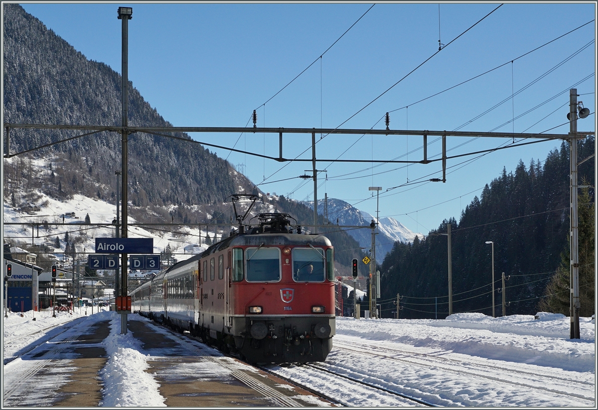 Bei kräftigem Gegenlicht erreicht die Re 4/4 II 11164 mit ihrem IR 2320 Locarno - Basel den Bahnhof Airolo. 
11. Feb. 2016