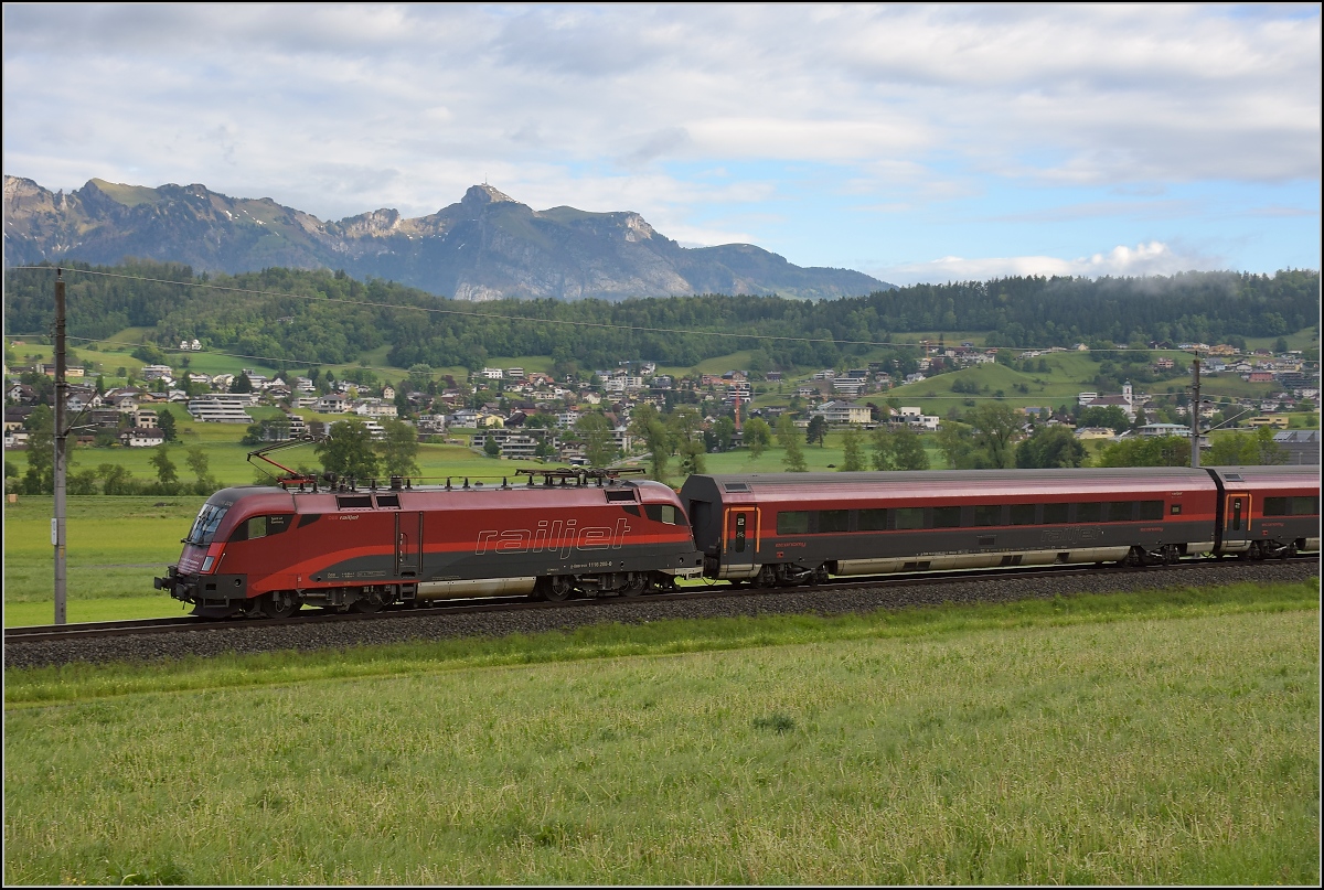 Bei Nendeln in Lichtenstein fährt 1116 208-0  Spirit of Germany  mit RJ 161 Zürich-Wien vorbei und freut sich im Jahr 2017 immer noch über die komplette Betriebsaufnahme des Wiener Hauptbahnhofs, wie man auf der Lokfront lesen kann. Im Hintergrund der Hohe Kasten. Mai 2017.