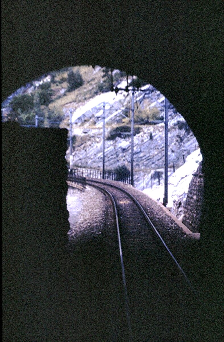 BLS-Strecke oberhalb des Rhonetals; die BLS hat bereits weit vorausschauend die Tunnel für eine zweigleisige Strecke gebaut, das Material jedoch nicht vollständig augebrochen. So blieb ein Felsblock im Bereich für das zweite Gleis stehen, der zum 2-gleisigen Ausbau  nur  abgetragen werden musste. Am 09.09.1980.
