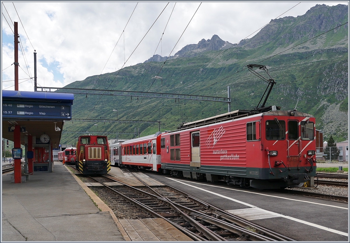 Da auf der steilen Schllenen Bahn die Anhngelast begrenzt ist, werden jeweils in Andermatt die von Visp kommenden Verstrkungswagen abgehngt und dann gleich dem Gegenzug bergeben. Hier holt die  Schma  Disellok nach der Ausfahrt des Zuges nach Gschenen die Wagen ab, whrend rechts der BDeh 4/4 54 (mit seinem Regionalzug nach Visp) fr das Ankuppeln der Verstrkungswagen bereit steht.
28. Juli 2016