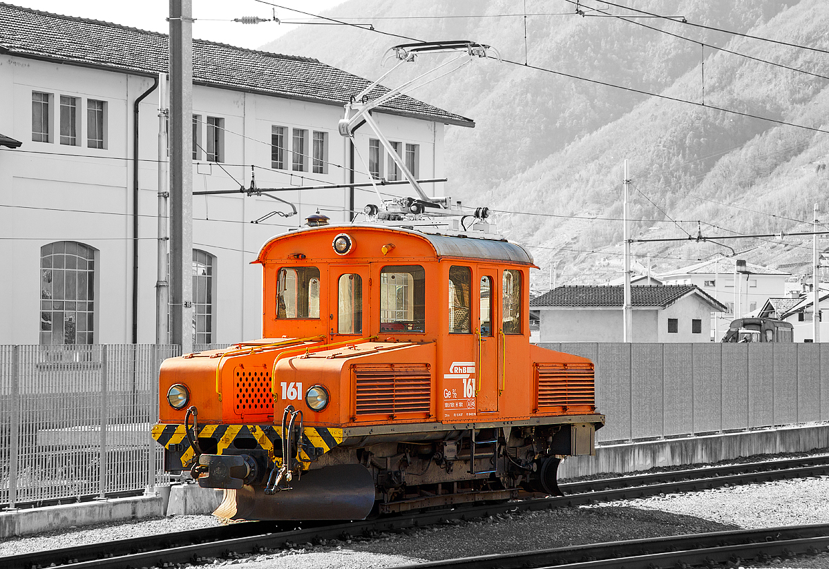 
Das RhB  Eselchen  161 bzw. der Rangiertraktor RhB Ge 2/2 161, ex BB Ge 2/2 61 steht am 18.02.2017 im RHB-Bahnhof Tirano. 

Der RHB-Bahnhof Tirano ist der Endbahnhof der Berninabahn und bedingt dadurch ein Kopfbahnhof. Bei den meist von Triebwagen geführten Züge werden dann die Personenwagen (teilweise auch Güterwagen) abgehangen und von der RhB Ge 2/2 auf ein anderes Gleis rangiert. Danach setzt der Triebwagen um und setzt sich für die Gegenrichtung wieder vor die Wagen.

Von der kleinen Elektrolokomotive Ge 2/2 wurden nur zwei Loks von diesem Typ für Berninabahn (BB) , heute der Rhätischen Bahn (RhB), gebaut, ursprünglich die BB 61 und BB 62, seit 1961 mit den Nummern RhB 161 und 162.

Beide Gleichstromloks wurden 1911 von der Berninabahn (BB) für Vorspanndienste beschafft, sie wurden von SIG und Alioth gebaut. Die damals noch braun lackierten Maschinen erhielten die Nummern Ge 2/2 61 und 62 und waren noch mit Lyra-Stromabnehmern bestückt. Nach der Übernahme der BB durch die RhB im Jahre 1942 wurden sie verschiedentlich modernisiert; sie tragen heute einen Einholmstromabnehmer und sind meistens als Rangierloks in Tirano und Poschiavo tätig.

Sie werden wegen ihrer Form auch  Mini-Krokodile  oder wegen ihres Aufgabenbereichs  Eselchen  genannt.  Zwischen den Vorbauten ist ein Gang, so dass ein Übergang zum Zug möglich war. Die Benutzung ungeschützter Übergänge ist aber inzwischen selbst dem Personal untersagt, so wurden folgerichtig an den beiden Loks die Übergangsbleche entfernt. Die Loks sind die zweitältesten im Dienst befindlichen Lok der RHB.

Technische Daten der Ge 2/2
Betriebsnummern: 161 und 162 (ex 61 und 62)
Hersteller: SIG, Alioth
Baujahr: 1911
Anzahl Fahrzeuge: 2
Spurweite: 1.000 mm
Achsanordnung: B
Länge über Puffer: 7.740 mm
Breite: 2.500 mm
Achsabstand: 
Triebraddurchmesser (neu): 975 mm
Dienstgewicht:  18.0 t
Höchstgeschwindigkeit: 45 km/h
Stundenleistung: 250 kW (340 PS)
Anfahrzugkraft: 37,6 kN
Stundenzugkraft: 27,5 kN bei 27 km/h
Motorentyp:  Gleichstrom Reihenschluss
Fahrleitungsspannung: 1 kV DC (Gleichstrom) / 750 V DC vor 1935 
