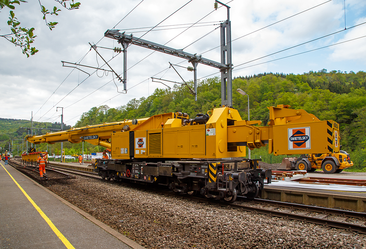 
Der 150 t KIROW Gleis- und Weichenbaukran KRC 1200 (ein Kirow MULTI TASKER KRC 1200) A-RTS 99 81 9119 004-5, ex SKL X 980 009-5, der Firma Swietelsky (eigestellt durch die Tochtergesellschaft RTS Rail Transport Service GmbH) ist am 14.05.2016 im Bahnhofs von Kautenbach (Luxemburg) im Einsatz. Der Kran hat die 50t-Traverse (Eigengewicht 5.600 kg) im Haken, an dieser befindet sich ein altes Gleisjoch welches aus dem Schotterbett gehoben ist.

Der Kran wurde 2002 von Kirow in Leipzig unter der Fabriknummer 114700 gebaut. Die Traverse wurde 2001 von in Leipzig unter der Fabriknummer 114700/1, Die Traverse kann beidseitig verlngert werden, dann hat sie eine Tragfhigkeit von 45t bei einem Eigengewicht von 7.200 kg.

TECHNISCHE DATEN von dem Kran:
Spurweite: 1.435 mm
Achsfolge: 1'A'1A'A1'A1'
Eigengewicht  (in Transportstellung) : 128,0 t  (ohne Gegengewichte)
Lnge ber Puffer:  15.000 mm  (+13.000 mm Gegenlastwagen)
Motorleistung:  254 kW bei 2.200 U/min
max. Geschwindigkeit im Zugverband: 120 km/h
max. Geschwindigkeit im Eigenantrieb: 19 km/h
Achsanzahl:  8 (in 4 Drehgestelle bzw. 2 Doppeldrehgestelle)
Drehzapfenabstand: 10.000 mm
Drehzapfenabstand im Drehgestell 1 und 2: 2.300 mm
Achsabstand in den Einzeldrehgestellen: 1.100mm
Ergebene Achsabstnde in m: 1,1 / 1,2 / 1,1/ 6,6 / 1,1 / 1,2 / 1,1
Treib- und Laufraddurchmesser: 730 mm (neu)
Radsatzlast mit Gegengewichtswagen:  max. 20,0 t
Hhe in Transportstellung:  4.300 mm
Breite in Transportstellung:  3.100 mm
max. Ausladung vor Puffer:  21.000 mm
max. Traglast bei max. Ausladung:  40 t
Grte mgliche Traglast: 150 t (abgesttzt)  / 120t (freistehend)
max. Hakenhhe:  24.000 mm
hintere Ausladung (Gegenwicht):  7,9 m–13,5 m (max. 5.600 mm ber Puffer)
Zul. Anhngelast: 150 t
Kleinster befahrbarer Radius: 90 m (120 m im Schleppbetrieb)
Kraftstofftank: 800 Liter (Diesel)

Besondere Ausstattung:
berhhenausgleich 180 mm
Schwenkradius  360
Absttzung teleskopierbar bis 8 m Absttzbasis
profilfreies Arbeiten bis  30