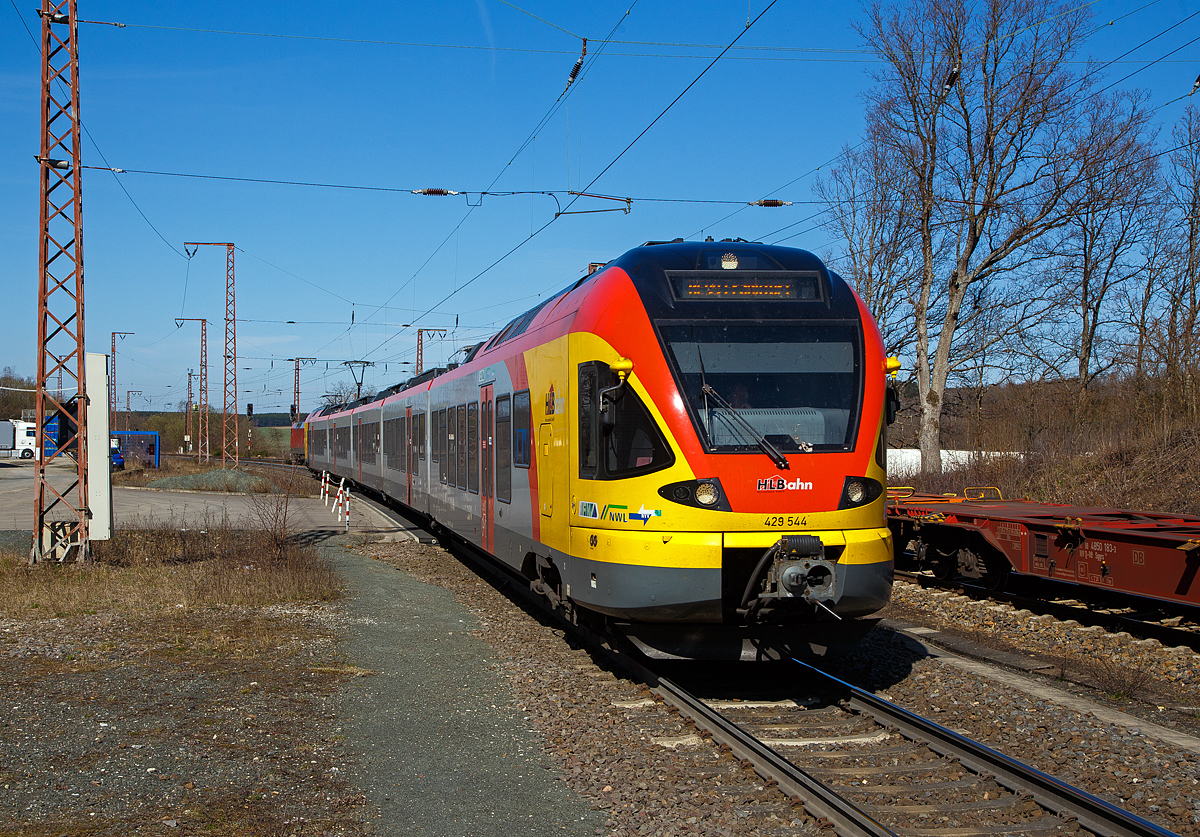 Der 5-teilige Stadler Flirt 429 544 / 429 044 der HLB (Hessischen Landesbahn) fährt am 30.03.2021, als RE 99  Main-Sieg-Express  (Siegen – Gießen – Frankfurt am Main Hbf), durch Rudersdorf (Kr. Siegen) über die Dillstrecke (KBS 445) in Richtung Gießen.

Hinten am Gleis hat die 152 124-4 der DB Cargo AG mit einem Containerzug noch Hp 0 und muss den Gegenverkehr abwarten. Ein Gleis war wohl unterbrochen.
