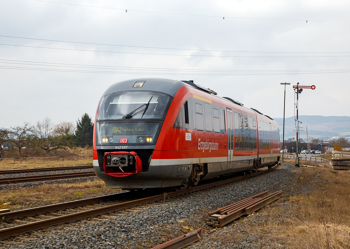 
Der Desiro 642 697 / 642 197 (95 80 0642 697-6 D-DB / 95 80 0642 197-7 D-DB)  Thermalbad Wiesenbad  der Kurhessenbahn fährt am 24.03.2018, als RB 42 von Brilon Stadt via Willingen nach Marburg/Lahn, durch (Lahntal-) Sarnau. 

Der Dieseltriebzug wurde 2003 von Siemens in Uerdingen unter den Fabriknummern 92939 und 92938 gebaut. Bis Dezember 2017 war er bei der Erzgebirgsbahn (DB Regio) im Einsatz, nun fährt er für die Kurhessenbahn (DB Regio).


Ende der 1990er Jahre schrieb die DB eine größere Anzahl von Dieseltriebwagen aus, mit dem Ziel, den Betrieb auf Nebenbahnen wirtschaftlicher zu gestalten und dort die verbliebenen lokbespannten Züge abzulösen. Es wurden gut 500 Triebwagen, aufgeteilt in acht Baureihen, bei der Fahrzeugindustrie bestellt. Die stückzahlenmäßig größte Baureihe war der Desiro von Düwag bzw. Siemens, er wurde als Baureihe 642 in 231 Exemplaren beschafft.


Technik und Aufbau:
Der Wagenkasten ist aus selbsttragenden Aluminiumröhre in Integralbauweise konstruiert. Die Kopfteile mit den Führerständen sind als vorgefertigte GfK-Module ausgeführt, die auf das verlängerte Untergestell des Aluminiumwagenkastens aufgeklebt sind.

Der Fahrgastraum ist gegliedert in den Niederflurbereich (von einem Einstieg bis zum Sitzbereich über dem Jakobsdrehgestell) und die höher gelegenen Bereiche an jedem Wagenende. Aufgrund des vergleichsweise großen Motorraums besitzt die Baureihe 642 jedoch einen geringeren Niederfluranteil als vergleichbare Züge wie zum Beispiel Bombardier Talent oder Alstom Lint. Glaswände und -türen trennen Einstiegsräume und Übergangsbereiche voneinander ab.

Der Fahrgastraum wird durch eine Warmwasser-Umluft-Heizung, bei extremer Kälte durch Ölfeuerung geheizt. Im Sommer soll die Klimaanlage für behagliche Temperaturen sorgen, allerdings sind die Anlagen noch immer störanfällig. Pro Wagen können sechs Fenster gekippt werden.


Fahrwerke und Bremsen
Zwei angetriebene Drehgestelle, ein nicht angetriebenes Jakobsdrehgestell mit Gummiprimärfedern und niveauregulierter Luftfederung in der Sekundärstufe. Je drei Wellenbremsscheiben
je Triebdrehgestell, zwei Radbremsscheiben je Radsatz im Jakobsdrehgestell. Magnetschienenbremse in den Triebdrehgestellen. Mikroprozessorgesteuerter Gleit- und Schleuderschutz. Die Triebwagen sind mit einer direkten elektropneumatischen Bremse (ep-Bremse) und einer indirekten mehrlösigen Druckluftbremse als Rückfallebene ausgestattet. Mit dem Retarder wird bei Nutzung der ep-Bremse zudem hydrodynamisch gebremst. Als Feststellbremse sind Federspeicherbremsen vorhanden. Die Magnetschienenbremse kommt bei Zwangs- und Schnellbremsungen zum Einsatz, bei Notbremsungen jedoch bleibt sie unwirksam. Zudem kann sie vom Triebfahrzeugführer über einen Kippschalter zugeschaltet werden.

Antrieb
Der Triebzug wir von zwei MTU 6-Zylinder-Dieselmotor mit Abgasturboaufladung, Ladeluftkühlung mit jeweils 275 kW / 374 PS Leistung (Euro II) bei 1900 U/min angetrieben. (Bei anderen Kunden und Ausführungen auch 315, 335 oder 360 kW, sowie Motoren von MAN)
Diese befinden sich jeweils unter dem Hochflurbereich zwischen dem angetriebenen Drehgestell und dem Niederflurbereich. Ihr Drehmoment wird über ein hydromechanisches Fünfgang-Automatikgetriebe mit Anfahrwandler und integriertem Retarder auf das äußere Drehgestell übertragen.

Technische Daten (DB Regio Version) : 
Spurweite:  1.435 mm (Normalspur)
Achsformel:  B´2´B´
Länge über Kupplung:  41.700 mm
Drehzapfenabstand: 2 x 16.000 mm
Achsabstand im Drehgestell: 1.900 / 2.650 /1.900 mm
Lauf- und Treibraddurchmesser: 770 mm (neu) / 710 mm (abgenutzt)
Breite:  2.830 mm
Größte Höhe: 3.819 mm
Fußbodenhöhen: 1.250 mm (Hochflur) / 575 mm (Niederflurbereich)
Eigengewichtgewicht: 68,2 t
Zul. Gesamtgewicht:  88,7 t
Höchstgeschwindigkeit:  120 km/h
Motoren: zwei MTU 6-Zylinder-Dieselmotor 
Leistung: 2 x 275 kW / 374 PS
Kraftübertragung: mechanisch (5-Gang-Automatikgetriebe mit hydraulischen Anfahrwandler)
Kraftstoffvorrat:  2 x 600 l
Heizölvorrat:  2 x 150 l
Max. Anfahrbeschleunigung: 1,1 m/s²
Max. Bremsverzögerung: Betriebsbremse 0,9 m/s² / Gefahrbremse 1,15 m/s²
Sitzplätze: 12 (1.Klasse) 109 (2.Klasse, davon 13 Klappsitze)
Stehplätze:  90
Scharfenberg Kupplung:  Typ 10

