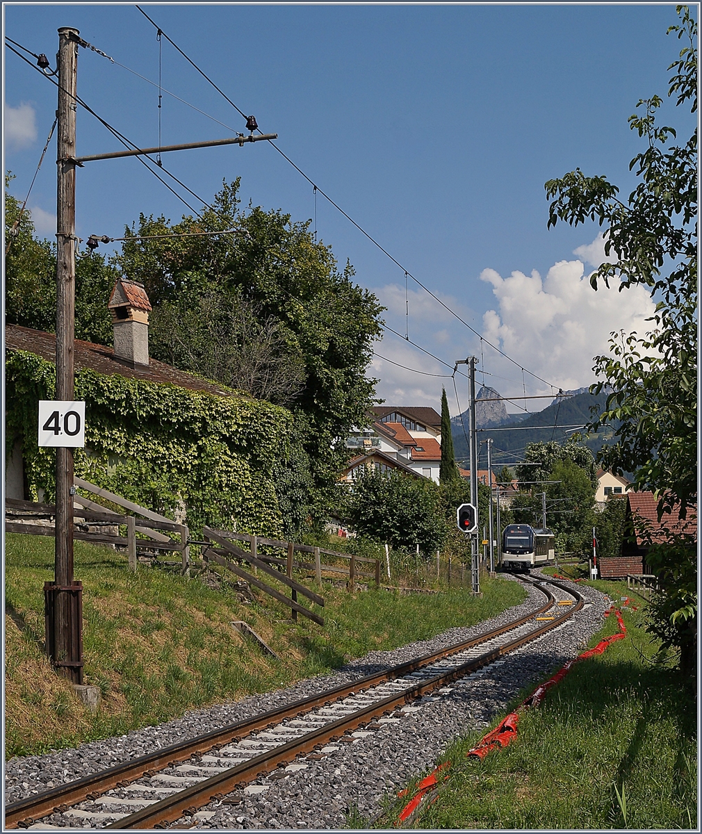 Der Fahrleitungsmast N 23 mag nicht ganz so alt sein wie der Dent de Jaman im Hintergrund, drfte aber schon eine Ewigkeit hier stehen. Als es vor gut fnfzehn Jahren darum ging, die Holzmasten durch Metalmasten zu ersetzen und dabei den Abstand von Mast zu Mast zu vergrssern, wehrte sich ein Anwohner mit Erfolg vor Gericht dagegen und so blieb der Fahrleitungsmast N 23 in St-Lgier stehen und trgt neuerdings sogar eine interessante Signaltafel mit der die hier einzuhaltende Hchstgeschwindigkeit angezeigt wird; bedeutend insofern, als dass die MVR die Hchstgeschwindigkeit seit dem 1. Juli 2019 um 25 % erhht hat und nun auf dafr ausgebauten Streckenabschnitten mit bis zu 50 km/h unterwegs ist.

30. Juli 2019