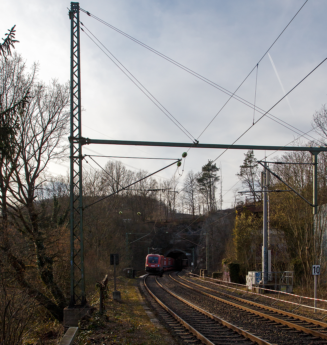 Der ÖBB Taurus 1016 041 (91 81 1016 032-5 A-ÖBB) fährt am 12.03.2022 mit einem  Winner -KLV-Zug bei Scheuerfeld (Sieg) durch den 32 m langen Mühlburg-Tunnel und über nachfolgende Siegbrücke in Richtung Siegen.

Der Taurus wurde 2001 vom Siemens-TS Werk in Linz unter der Fabriknummer 20389 gebaut und an die ÖBB - Österreichische Bundesbahnen geliefert.