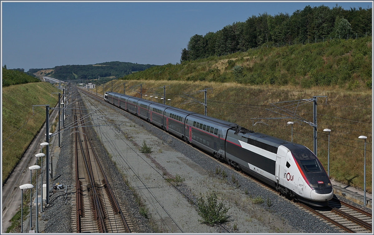 Der SNCF TGV 4712, unterwegs als TGV 9896 von Montpellier nach Luxembourg, erreicht seinen nächsten Halt, den Bahnhof Belfort-Montbéliard. Im noch knapp zu erkennen, der 816 Meter lange Viaduc de la Savoureuse. 

23. Juli 2019
