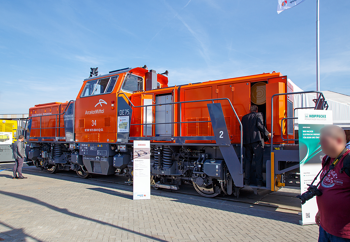 Der zur ZAGRO Group gehrende Hersteller  GMEINDER LOKOMOTIVEN GmbH (Mosbach) prsentierte auf der InnoTrans 2018 in Berlin (hier 18.09.2018) seine Rangierlokomotive mit elektrischer Leistungsbertragung DE75 BB Dual Engine, hier in Form der ArcelorMittal 34, NVR-Nummer 92 80 1075 034-9 D-GL.

Die DE 75 BB Dual Engine wurde 2018 von Gmeinder in Mosbach unter der Fabriknummer 5777 gebaut und hier auf der Messe  InnoTrans 2018  ausgestellt bevor sie dann an die ArcelorMittal Eisenhttenstadt Transport GmbH in Eisenhttenstadt als Lok 34 ArcelorMittal 1075 034-9 ausgeliefert wurde.

Die DE75 BB ist eine robuste Rangierlokomotive fr den schweren Rangierdienst. Die elektrische Leistungsbertragung mit vier unabhngig geregelten Fahrmotoren ermglicht die optimale Ausnutzung der Adhsion und gleichzeitig die Verwendung verschiedenster Energiequellen. Durch den symmetrischen Aufbau der Lokomotive knnen zwei Energiequellen eingebaut werden, zum Beispiel (wie hier) zwei Diesel-Generator-Aggregate (Dual-Engine Lokomotive) oder ein Dieselaggregat und ein Lithium-Ionen-Batteriesatz (Hybridlokomotive). Auch eine Energiezufhrung ber Stromschiene (DC 750 V) oder Fahrdraht ist mglich. Der symmetrische Aufbau der Lokomotive setzt sich auch in der Leistungselektronik fort. Zwei unabhngige Teilsysteme gewhrleisten hchste Verfgbarkeit der Lokomotive.

Die ist zugelassen, Zugfahrten auerhalb von Bahnhfen sind jedoch nicht mglich, da der Erstkunde Arcelor Mittal die Lok ohne Zugsicherung und Zugfunk geordert hat. 

TECHNISCHE DATEN der DE75 BB Dual Engine:
Hersteller:	GMEINDER LOKOMOTIVEN GmbH (Mosbach)
Spurweite:  1.435 mm
Achsformel: Bo‘ Bo‘
Lnge ber Puffer: 14.080 mm
Drehzapfenabstand: 5.600 mm
Achsabstand im Drehgestell: 2.400 mm
Breite: 3.080 mm
Hhe: 4.260 mm
Dienstgewicht: 80 t
Achslast: 20 t
Hchstgeschwindigkeit: 100 km/h
Min. Dauerfahrgeschwindigkeit: kleiner 1,0 km/h
Motorleistung: 2 x 354 kW
Leistung am Rad: 600 kW 
Anfahrzugkraft: 260 kN
Kleinster befahrbarer Gleisbogen: R  60 m
Tankinhalt: 1.900 Liter
Sandvorrat: 500 kg
Fahrzeugbegrenzung:   UIC 505-1
