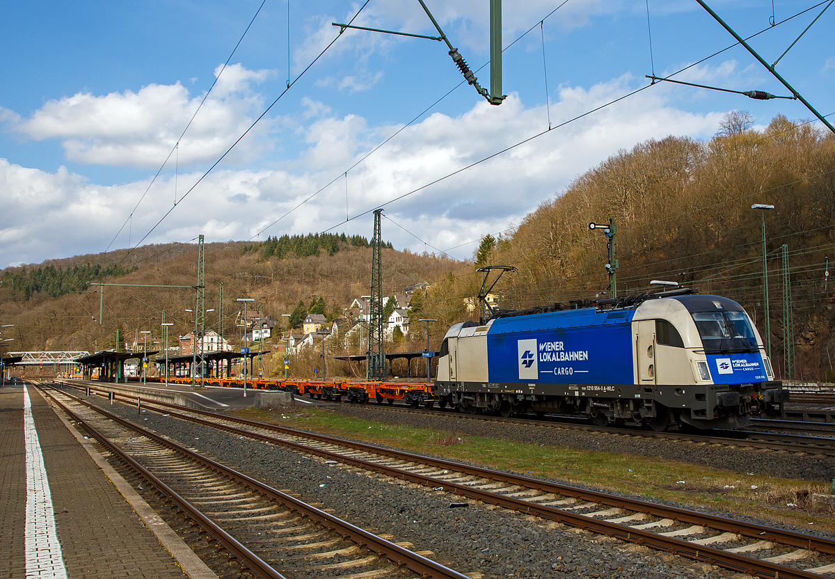 Die 1216 954 (91 81 1216 954-8 A-WLC) der WLC - Wiener Lokalbahnen Cargo GmbH (Wien), fährt am 26.03.2021 mit einem Leerzug, neuer 4-achsiger Drehgestell - 40‘ Containertragwagen der Gattung Sgmmnss 738 der WASCOSA AG Z, durch Dillenburg in Richtung Gießen.

Die Taurus III bzw. Siemens ES 64 U4-C (Variante C für Österreich, Deutschland, Tschechien und die Slowakei) wurde 2010 unter der Fabriknummer 21415 von Siemens gebaut und an die WLC geliefert.
