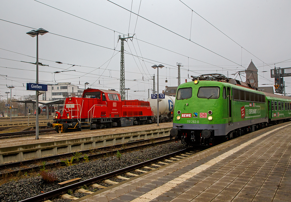 Die 261 056-6 (92 80 1261 056-6 D-DB) eine Voith Gravita 10 BB der DB Cargo AG, kam am 12.11.2021 mit einem Kesselwagenzug von den Oberhessischen Strecken, der Lahn-Kinzig-Bahn (KBS 631) oder Vogelsbergbahn (KBS 635), in Gießen an und hatte kurz Hp 0. Nun geht es auf die Main-Weser-Bahn (KBS 630). Rechts steht die Bügelfalten E10, die 110 292–0 (91 80 6110 292-0 D-GfF) der Gesellschaft für Fahrzeugtechnik mbH mit dem REWE - Supermarkt-Zug.

Die Voith Gravita 10 BB wurde 2011 unter der L04-10107 gebaut und ausgeliefert.
