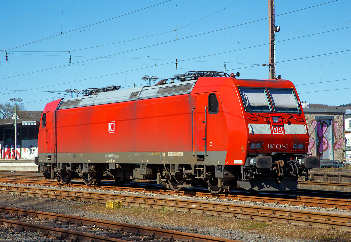 Die allererste der Baureihe 185....
Die 185 001-5 (91 80 6185 001-5 D-DB) der DB Cargo AG ist am 04.04.2020 in Kreuztal abgestellt.
Die TRAXX F140 AC wurde 2000 von DaimlerChrysler Rail Systems (Adtranz) in Kassel unter der Fabriknummer 33398 gebaut. Die Abnahme durch die DB Cargo erfolgte erst Anfang Dezember 2002.

Auf Grund der wachsenden internationalen Aktivitäten von DB Cargo wurde für neue elektrische Güterzuglokomotiven Zweisystemfähigkeit für den Einsatz mit 25 Kilovolt bei 50 Hertz gefordert, um mit den Lokomotiven auch Frankreich, Luxemburg und Dänemark anfahren zu können. Die bestehende Option auf weitere Lokomotiven der Baureihe 145 wurde daher entsprechend abgewandelt wahrgenommen.

Im Januar 2000 konnte der Hersteller Adtranz (ab 2001 Bombardier) mit der 185 001 das erste Exemplar einer Mehrsystemvariante der Baureihe 145 präsentieren. Technisch sind die 185er eine Weiterentwicklung der 145, auch flossen Erkenntnisse aus der Entwicklung der Baureihe 146 in die Lokomotiven mit ein. Insgesamt wurden 405 Lokomotiven der Baureihe 185 (200 F140 AC1 sowie 205 F140 AC2) beschafft, wodurch diese die derzeit am häufigsten im deutschen Eisenbahnnetz anzutreffende Elektrolokomotive ist. Mit ihr wurden vor allem die alten Lokomotiven der Baureihe 140 ersetzt. Der Stückpreis einer Lokomotive der Baureihe 185 betrug im Jahr 2000 circa 4,85 Millionen DM (rund 2,5 Millionen Euro).
