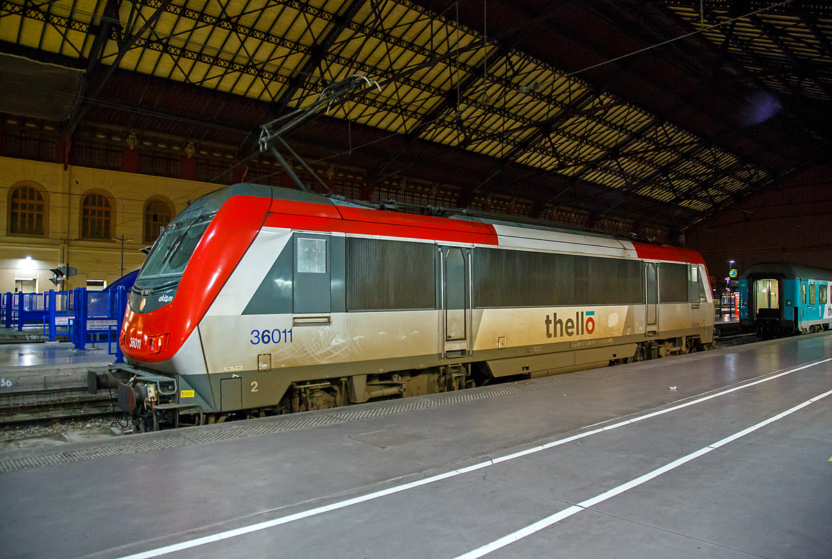 Die an Thello vermietete Akiem 36011 (91 87 0036 011-1 F-AKIEM), eine Alstom BB 36000  Astride  (Asynchron Tricurrent Drive Engine) am 24.03.2015 im Bahnhof Marseille Saint-Charles. Zuvor hatte sie mit dem mit dem Thello EC 159 (Mailand - Genua  - Monte-Carlo - Niza - Toulon - Marseille-St-Charles) ihren Endbahnhof erreicht.

Die Thello S.A.S. mit Sitz in Paris ist französisches Eisenbahnverkehrsunternehmen, das aber der italienischen Trenitalia gehört. Thello war das erste Unternehmen, das die Konkurrenz im Schienenpersonenfernverkehr mit der SNCF aufnahm, nachdem der Markt für internationale Fernverkehrsverbindungen ab 2009 in Frankreich liberalisiert wurde. Thello betreibt Expresszüge zwischen Frankreich und Italien.

Die Lok ist eine BB 36000 welche eine Baureihe von elektrischen Lokomotiven der SNCF, mit dem Kosename  Astride  (Asynchron Tricurrent Drive Engine). Gebaut von Alstom (ehem. GEC-Alsthom), reihen sie sich ein in die Kategorie der europäischen asynchronen Mehrsystem-Lokomotiven. Mit ihren  großen  Schwestern, den BB 26000  Sybic  zählen sie zu den stärksten Lokomotiven der SNCF.

Die Astride besitzen drei unterschiedliche Stromabnehmer (1,5 kV Gleichstrom, 3 kV Gleichstrom und 25 kV 50 hz Wechselstrom). Diese Loks können in Belgien, in Luxemburg, in Italien, in Frankreich und neuerdings sogar in den Niederlanden verkehren. So sollte ein Lokwechsel an den Grenzen vermieden und eine Menge Zeit eingespart werden.

Nach der Bestellung von 264 Lokomotiven der Baureihe BB 26000  Sybic  entschied sich die SNCF für einen Kontraktwechsel. Daher bekamen die letzten 30 Neubau-Lokomotiven eine Drehstromausrüstung mit Asynchron-Motoren. Doch niemand zeigte Interesse an den neuen Loks. Genau zum selben Zeitpunkt wurden nämlich der Personenverkehr vom Güterverkehr bei der SNCF getrennt. Für den Personenverkehr wurde der TGV in den Focus gestellt und die meisten internationalen Nachtzüge abgeschafft. Der Güterverkehr zeigte auch kein Interesse an dieser polyvalenten Lok. Ebenfalls zu diesem Zeitpunkt, begann Alstom mit der Entwicklung der Prima, von der sie sich höhere Renditen erhoffte, sowohl in Frankreich, als auch im Ausland. Unter diesen Umständen war es schwer für die „Astride“ sich durchzusetzen, zu allem Übel litt sie auch noch lange unter verschiedenen Kinderkrankheiten.

Die insgesamt 60 gebauten BB 36000 „Astride“ wurden zwischen 1996 und 2002 ausgeliefert. Sie können eine gewisse Familienzugehörigkeit mit den BB 26000 nicht verleugnen, auch wenn die Ecken etwas abgerundet wurden und sie aerodynamischer ist, als die Sybic.

Obwohl sie Personenzüge mit 200, ja sogar 220 km/h ziehen kann, so wurde die „Astride“ doch vorwiegend im Güterverkehr zwischen Belgien und Italien eingesetzt. Dort ist ihre Geschwindigkeit allerdings auf 120 km/h begrenzt.

Im Oktober 2011 kamen die Loks mit den Nummern BB 36001,2,4,5,7,11 und 15 zu Akiem. Sie behielten zwar ihre  livrée multiservice , haben aber das SNCF Logo verloren. Drei von diesen Loks (BB36007, BB36011, BB36015) wurden bis 200 km/h getestet und fahren jetzt im internationalen Personenverkehr zwischen Paris und Venedig, sowie Marseille und Mailand. Diese Verbindungen werden von Thello, einer Tochtergesellschaft von Veolia betrieben.

Technische Daten der Baureihe BB 36000  Astride :
Betriebsnummern : 36001-36030, die 36331-36360 Italien tauglich, Mehrfachtraktion
Hersteller: GEC-Alsthom
Spurweite: 1.435 mm
Bauart: Bo'Bo'
Stromsystem: 1.500 V DC; 3.000 V DC und 25 kV, 50 Hz AC
Baujahre: 1996-2002

Länge über Puffer: 19.110 mm
Achsabstand im Drehgestell: 3.000 mm
Drehzapfenabstand: 10.400 mm
Breite: 2.926 mm
Höhe: 4.270 mm
Dienstgewicht: 89 t
Triebraddurchmesser (neu): 1.150 mm
Höchstgeschwindigkeit: 200 km/h (wenige 220 km/h)
Dauerleistung: 5.600 kW
Anfahrzugkraft: 320 kN
Anzahl der Fahrmotoren: 4 (4 FXA 4559 Alstom Asynchronmotoren mit Zwangsbelüftung)