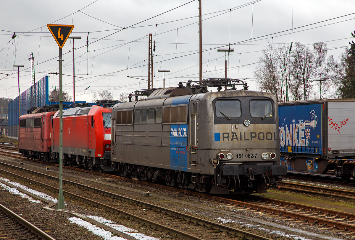 Die DB Cargo AG vermietete Railpool 151 062-7 (91 80 6151 062-7 D-Rpool) steht am 08.012022 in Kreuztal in der Abstellgruppe. Dahinter stehen noch die DB Cargo 185 002-3 und die Railpool 151 0086-6.

Die Lok wurde 1974 von Henschel & Sohn in Kassel unter der Fabriknummer 31805 gebaut und an die Deutsche Bundesbahn geliefert. Bis 31.12.2016 gehörte sie zur DB Cargo AG. Zum 01.01.2017 wurden je 100 sechsachsige elektrische Altbau-Lokomotiven der Baureihen 151 und 155 an ein Konsortium aus dem Lokvermieter Railpool verkauft. Die DB Cargo mietet daraufhin 100 Loks von Railpool wieder an. Die anderen Maschinen werden dem freien Markt angeboten.

Wie auch die Werbung auf  ihr zeigt: Die Lok gibt es im Maßstab 1:1 bei RAILPOOL und im Maßstab 1:87 bei Roco und im Maßstab 1:160 bei Fleischmann. Wobei mir persönlich gefällt sie in der Farbgebung nicht gerade. Zudem könnte sie mal eine Wäsche vertragen.
