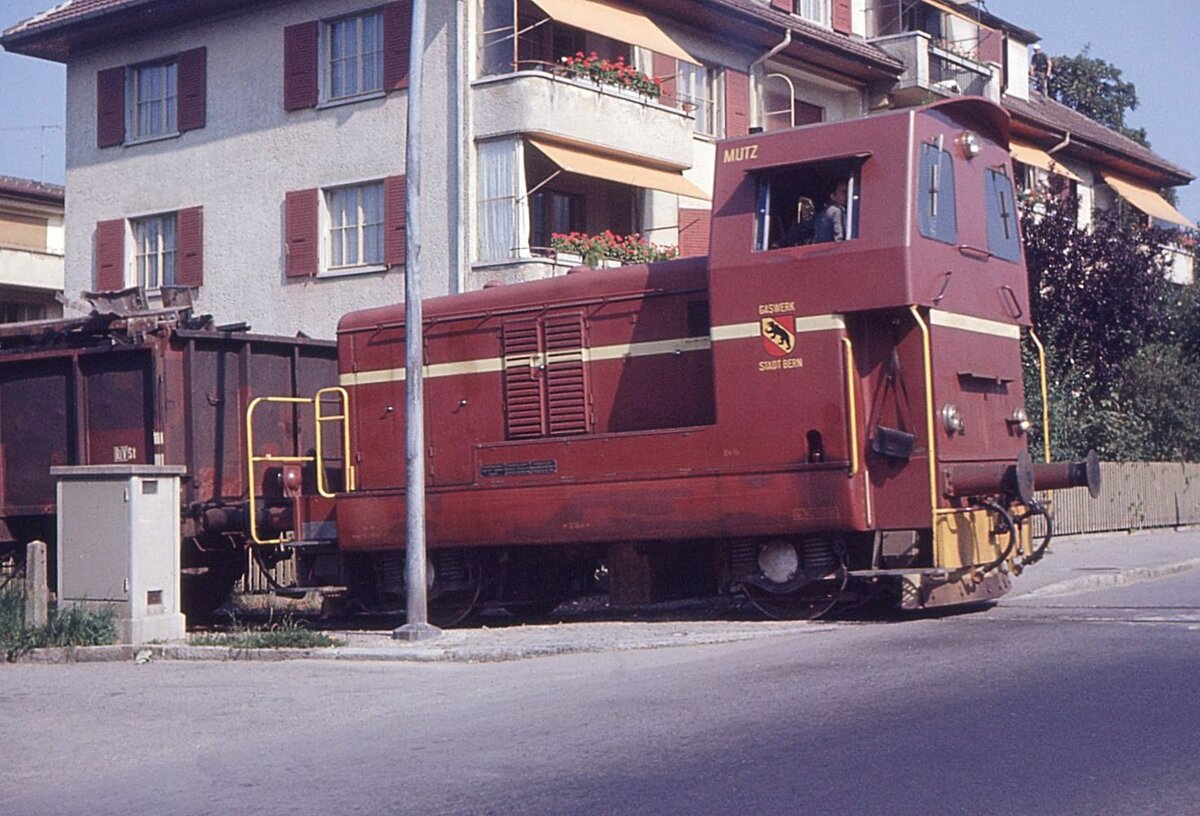 Die Diesellok  Mutz  der Gaswerkbahn Bern; hier beim Ueberqueren der stark befahrenen Seftigenstrasse in Wabern. Die Lok vom Typ Em 2/2 wurde in 9 Exemplaren gebaut(1959-1967) von BBC/SIG/Saurer. Der 330 PS starke  Mutz  kam 1961 auf die Gaswerkbahn Bern und wurde nach Schliessung dieser Bahn an die Sihltalbahn (SZU) verkauft, von wo er 2014 zur Zürcher Museumsbahn gelangte. Als Detail fällt die Zugführertasche auf, die unterhalb des Führerstands hängt. Aufnahme 23.August 1968, wo die Lok nach Schliessung des Gaswerks im Dezember 1967 mit dessen Abbruch beschäftigt ist.  