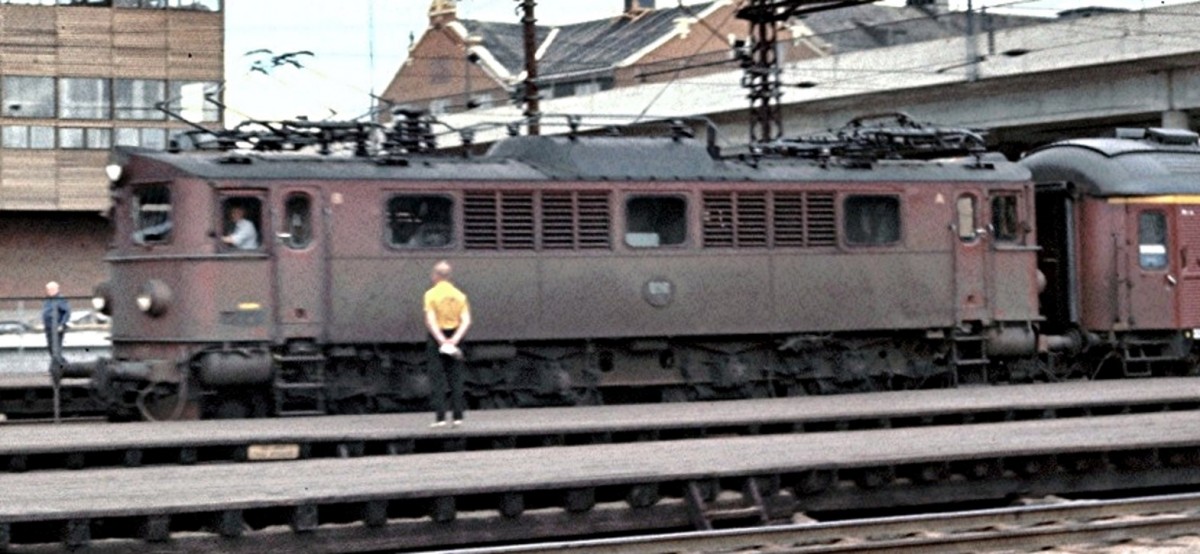 Die Ellok Typ F der SJ mit Achsfolge 1'Do1'steht in Oslo am Bahnsteig im Juli 1971. Diese alte, Aufnahme, mit einer einfachen Kamera aufgenommen, aus großer Entfernung, habe ich gewählt, weil hier auch der damals aus Holzplanken betehende Bahnsteig im Hauptbahnhof Oslo zu sehen ist. Ein Detail welches kaum auffällt - wenn man nicht an den aus den Planken hochstehenden Nägeln hängenbleibt. (Diascan). 