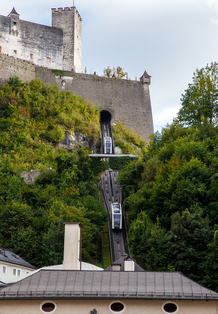 Die FestungsBahn Salzburg am 10.09.2002.

Die FestungsBahn Salzburg ist eine Standseilbahn in der Stadt Salzburg, die zur Festung Hohensalzburg hinaufführt. Die Festung ist eine der größten bestehenden Burganlagen Europas aus dem 11. Jahrhundert. Unter dem Markennamen FestungsBahn wird die Bahn seit 2000 von der Salzburg AG (zuvor SLB) betrieben. Um Jahrhunderte älter ist aber von Nonnberg auf die Festung führend der Reißzug, die älteste bis heute betriebene Materialseilbahn weltweit.

Die Festung Hohensalzburg ist eine der größten bestehenden Burganlagen Europas aus dem 11. Jahrhundert. Die FestungsBahn ist Österreichs älteste, in Betrieb befindliche Standseilbahn. Seit 1892 bringt sie Besucher schnell und sicher auf die Festung. Schon während der Fahrt kann man einen atemberaubenden Blick auf die Stadt Salzburg werfen und oben angekommen lädt das Panorama über Salzburg zum Träumen ein.

Die FestungsBahn ist Österreichs älteste, in Betrieb befindliche Standseilbahn. Sie bringt seit 1892 Besucher schnell und sicher auf die Festung Hohensalzburg. Bis 1959 wurde die FestungsBahn als „Tröpferlbahn“ mit Wasser aus dem Almkanal betrieben, heute ist die Standseilbahn elektrisch unterwegs. In weniger als einer Minute sind die Wagen mit 55 Personen auf der Festung Hohensalzburg. Schon während der Fahrt kann man einen atemberaubenden Blick auf die Stadt Salzburg werfen und oben angekommen lädt der Blick über die Dächer der Stadt zum Staunen ein.  

Elektrische Bahn:
Die Wasserbahn wurde samt Strecke abgetragen und eine neue Gleisanlage mit zwei Wagen installiert. Im April 1960 ging die elektrisch angetriebene Bahn in Betrieb. Die Fahrgeschwindigkeit verdoppelte sich (1,0 m/s auf 2,4 m/s), die neuen Wagen boten Platz für 36 Fahrgäste. Eine Fahrt von der Talstation zur Festung dauerte somit nur noch 80 Sekunden, weniger als die Hälfte der „offiziellen“ Fahrzeit der früheren Wasserbahn.  

Umbau 1991:
40 Millionen Fahrgäste in 31 Jahren machten eine Generalmodernisierung nötig. Wurde zuerst noch an eine kleine Lösung mit Austausch der Wagenkästen gedacht, so entschloss man sich per 1.9.1989 zur Erneuerung des Antriebes und der Wagen als wirtschaftlichste Lösung. Im November 1991 begannen in der Bergstation die Umbaumaßnahmen. Mit dem Neubau wurde die Fahrgeschwindigkeit auf 5 m/s, das Fassungsvermögen auf 48 Personen erhöht. Um dem Fahrgast einen schönen Ausblick auf die Stadt zu ermöglichen, wurden die neuen Wagen mit der damals größtmöglicher Verglasung, speziell auch im Dachbereich, ausgeführt.

Modernisierung 2011:
Nach knapp 19 Jahren kam das Ende der dritten Festungsbahngeneration. Von Januar bis April 2011 wurde die FestungsBahn modernisiert. Die Modernisierung der FestungsBahn wurde der Siemens-Division Industry Solutions Siemens als Generalunternehmer übertragen. Die Firma Carvatech war für den Kabinenaufbau verantwortlich und die Doppelmayr Cable Car GmbH für das Fahrwerk und die mechanischen Komponenten. Rund 4 Millionen Euro wurden in zwei neue Fahrzeuge und die Erneuerung der elektrotechnischen Ausrüstung investiert. Die Wagen werden auf Berg- und Talfahrt von dem jeweils bergseitigen Führerstand aus gesteuert. Die großen Panoramafenster bieten einen optimalen Ausblick auf die Altstadt. Stündlich können bis zu 1.850 Fahrgäste befördert werden.

TECHNISCHE DATEN:
Antrieb: frequenzgeregelter Drehstrommotor (400 V)
Antriebsleistung: 225 kW
Wagenkapazität: 55 Pers. (54 + 1 Wagenbegleiter, bergseitig) auf 3+1 Ebenen
Geschwindigkeit: 5 m/sec.(maximal 5,5)
Spurweite: 1.040 mm
Schräge Länge: 198,5 m 
Höhenunterschied: 102 m
Größte Steigung: 62 % 
Seildurchmesser: 25 mm
Fahrzeit: 48 sec. (ohne Halt auf halber Strecke)
Transportkapazität : 1.850 Pers./h 
Gewicht eines Wagens: 4.125 kg
Wagenlänge: 9.300 mm
