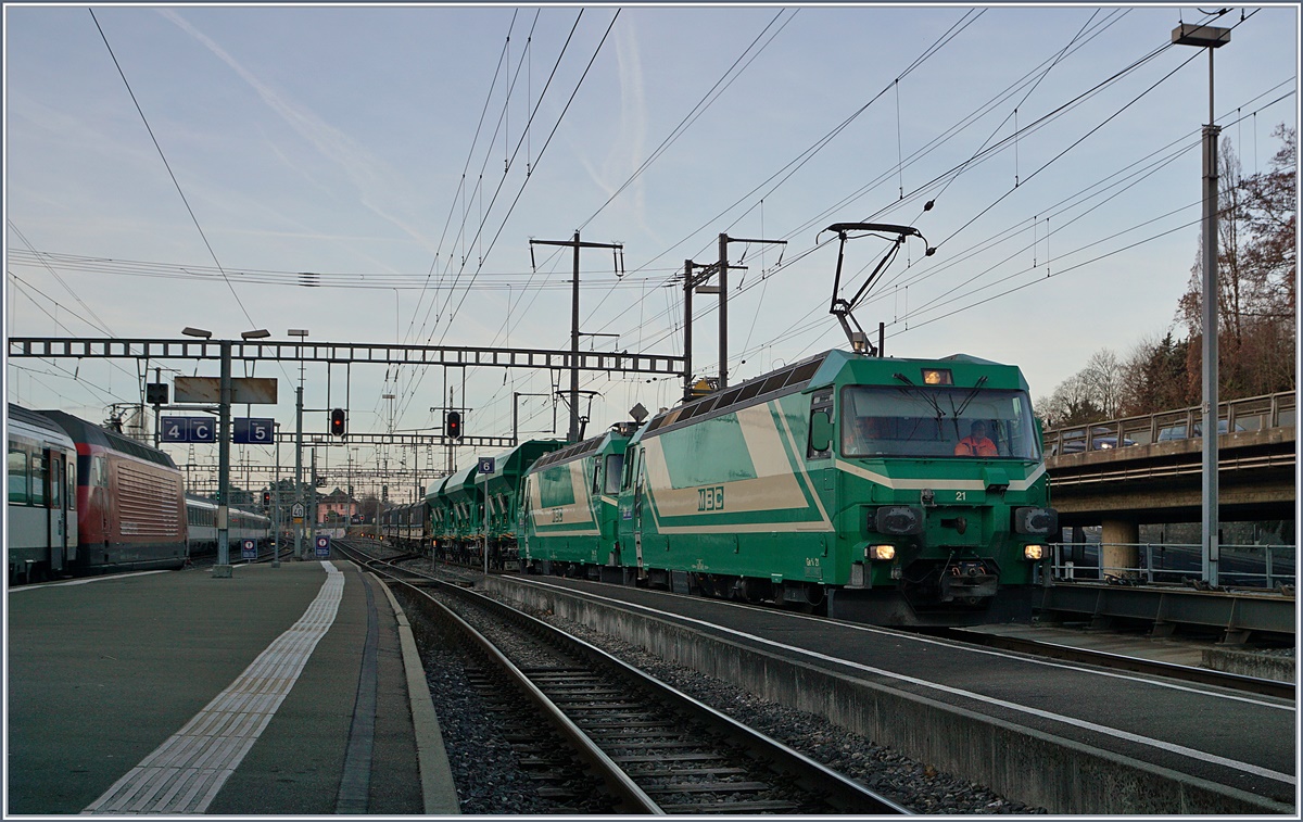 Die Kreuzung zweier Züge geschieht in der Regel, dass die beiden aus unterschiedlichen Richtung kommenden Züge sich kreuzen und dann weiter fahren. Seit kurzem kreuzen sich in Morges leere und volle Schüttgutgüterzüge der BAM MBC, die dabei auch die Traktion, Spurweite und Fahrrichtung wechseln. 
Ein Kaisermanöver vom Feinsten, welches hier Schritt für Schritt gezeigt werden soll: 
Während die Re 4/4 II (UIC 91 85 4420 506 8 CH MBC) mit ihrem leeren Zug von Gland schon vor meiner Ankunft ankam und nun im östlichen Bahnhofskopf auf einem Ausziehgleis wartet, erreicht der volle Schüttgutzug mit den beiden Ge 4/4 21 und 22 Morges.
22. Feb. 2017