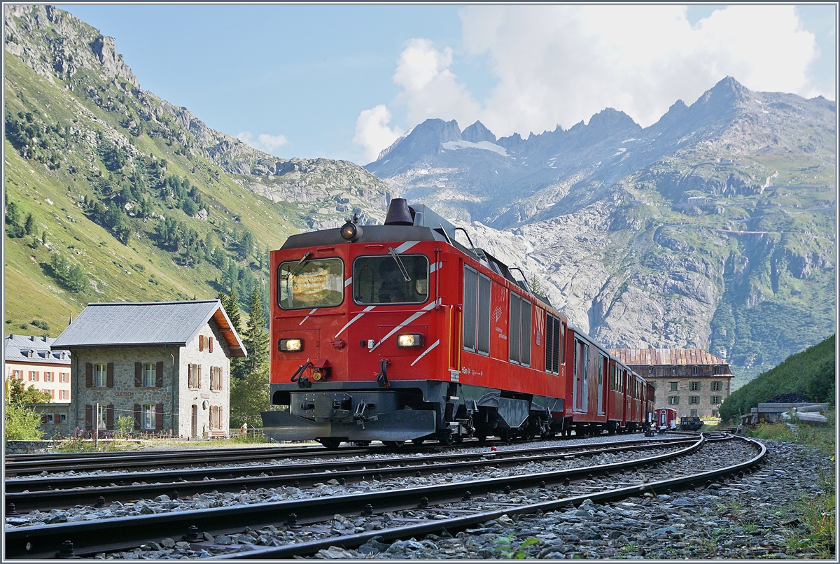 Die MGB HGm 4/4 61 (Baujahr 1967) wartet mit ihrem Personenzug 325 in noch schattigen Bahnhof von Gletsch auf die Weiterfahrt nach Oberwald.

31. August 2019