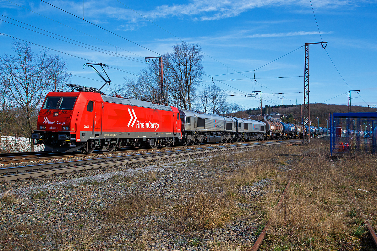 Die RHC 2056 bzw. 185 588-1 (91 80 6185 588-1 D-RHC) der RheinCargo GmbH & Co. KG, ex 2056 (91 80 6185 588-1 D-HGK) der HGK - Häfen und Güterverkehr Köln AG fährt am 20.03.2021, durch Rudersdorf (Kr. Siegen) über die Dillstrecke (KBS 445) in nördlicher Richtung. Im Schlepp bzw. am Haken hat sie die beiden Class 66 (EMD JT42CWR) die RHC DE 670 (92 80 1266 070-2 D-RHC) und die RHC DE 672 (92 80 1266 072-8 D-RHC), sowie einem mit Dieselkraftstoff beziehungsweise leichtes Heizöl (laut Gefahrstofftafel 30/1202) beladenen Kesselwagenzug bestehend aus Wagen der Gattung Zacns

Die RheinCargo ist ein 2012 gegründetes Gemeinschaftsunternehmen der Häfen und Güterverkehr Köln AG und der Neuss-Düsseldorfer Häfen GmbH & Co. KG (NDH), die jeweils zu jeweils 50 % Eigentümer sind. 

Lebensläufe der Loks:
Die TRAXX F140 AC2 (185 588-1) wurde 2008 von Bombardier in Kassel unter der Fabriknummer 34207 gebaut. Zulassungen hat die Lok für Deutschland, Österreich und die Schweiz, sie hat auch vier Stromabnehmer. Eigentlicher Eigentümer ist die AKIEM SAS, die zum 23.04.2020 das Leasinggeschäft für Schienenfahrzeuge von der Macquarie European Rail Limited (Luxembourg), ehemals CBRail übernommen hat.

Die beiden EMD JT42CWR (auch bekannt als Class 66) wurde 2003 von EMD (Electro-Motive Division eine Tochter von General Motors) gebaut, die RHC DE 670 (92 80 1266 070-2 D-RHC), ex HGK DE 170, unter der Fabriknummer 20028453-3 und die DE 672 (92 80 1266 072-8 D-RHC), ex HGK DE 172, unter der Fabriknummer 20028453-5. Eigentümer und Vermieter der beiden Class 66 ist die Beacon Rail Leasing Ltd in London, bis zum Verkauf zum 01.01.2007 war  es die HSBC Rail Ltd., London.