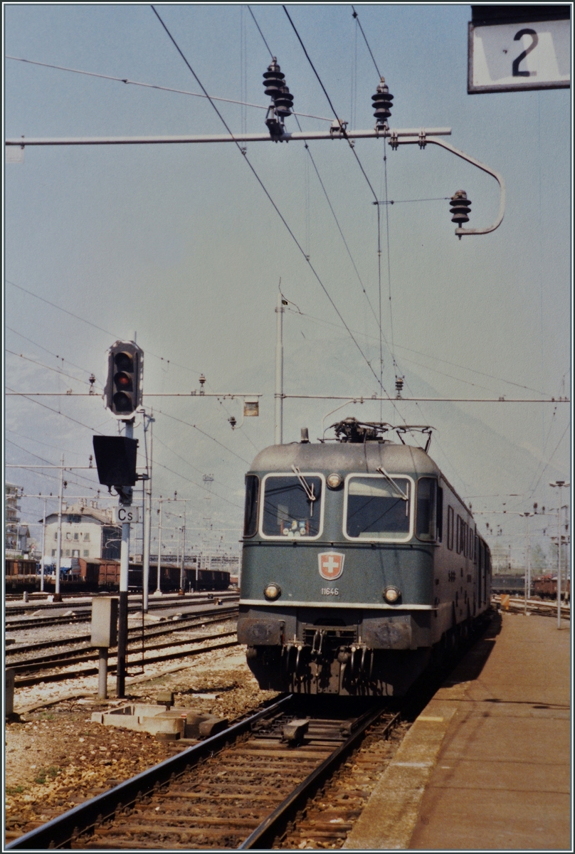 Die SBB Re 6/6 11646  Bussigny  mit einem Reisezug den Bahnhof von Domodossola, mehr Info gibt mein Fotoalbum leider nicht Preis, daf�r sind aus dem Bild einige Details zu sehen, wie z.B. eine weitere SBB Re 6/6 im Hintergrund und etliche abgestellte G�terwagen. Das Analogbild entstand im Fr�hling 1987