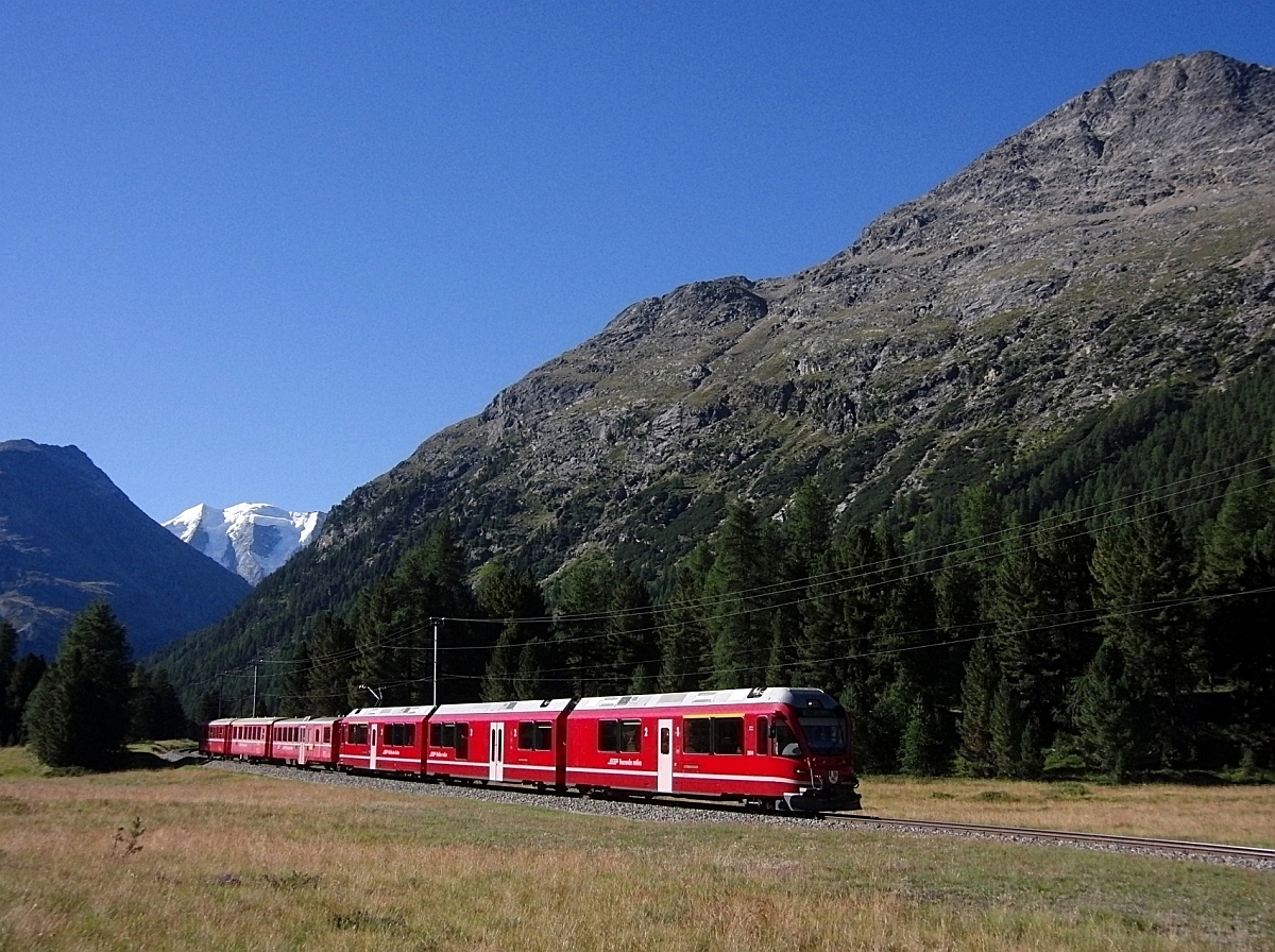 Die schneebedeckten Berge der Bernina-Gruppe und der talwärtsfahrende R 1632 von Tirano nach St. Moritz am 19.08.2012 zwischen den Stationen Morteratsch und Surovas.