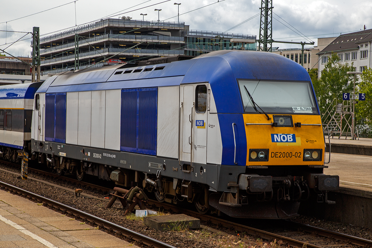 Die Siemens ER20 - DE2000-02 (92 80 1223 054-8 D-NOB) der Nord-Ostsee-Bahn GmbH steht am 16.06.2015 im Bahnhof Hamburg-Altona mit dem NOB Zug nach Westerland auf Sylt zur Abfahrt bereit.

Die ER 20 wurde 2005 von Siemens 21180 gebaut. Siemens Eurorunner ist eine dieselelektrische Lokomotive der mittleren Leistungsklasse, ein MTU 16 V 4000 R41 16-Zylinder Common Rai Dieselmotor mit einer Leistung von 2.000 kW (2.719 PS) treibt einen angeflanschtem Drehstrom-Asynchrongenerator an, der erzeugt dabei den Strom, mit dem die vier Motoren (einer für jede Achse) angetrieben werden. Bei erhöhtem Leistungsbedarf wie zum Beispiel beim Anfahren oder auf kurzen Steigungsabschnitten kann die Zugsammelschiene (für die Energieversorgung der Wagen) abgeschaltet werden, sodass die gesamte elektrische Leistung für die Fahrmotoren genutzt werden kann.

TECHNISCHE DATEN:
Achsformel:  Bo’Bo’
Spurweite:  1435 mm (Normalspur)
Länge über Puffer:  19.275 mm
Breite:  2.870 mm
Drehzapfenabstand:  10.362 mm
Achsabstand im Drehgestell:  2.700 mm
Kleinster bef. Halbmesser:  100 m
Dienstmasse:  80 t
Höchstgeschwindigkeit:  140 km/h
Installierte Leistung:  2.000 kW
Motorentyp:  Common Rail System
Motorbauart:  MTU 16 V 4000 R41
Nenndrehzahl:  600 - 1.800/Minute
Leistungsübertragung:  dieselelektrisch
Tankinhalt:  2800 l