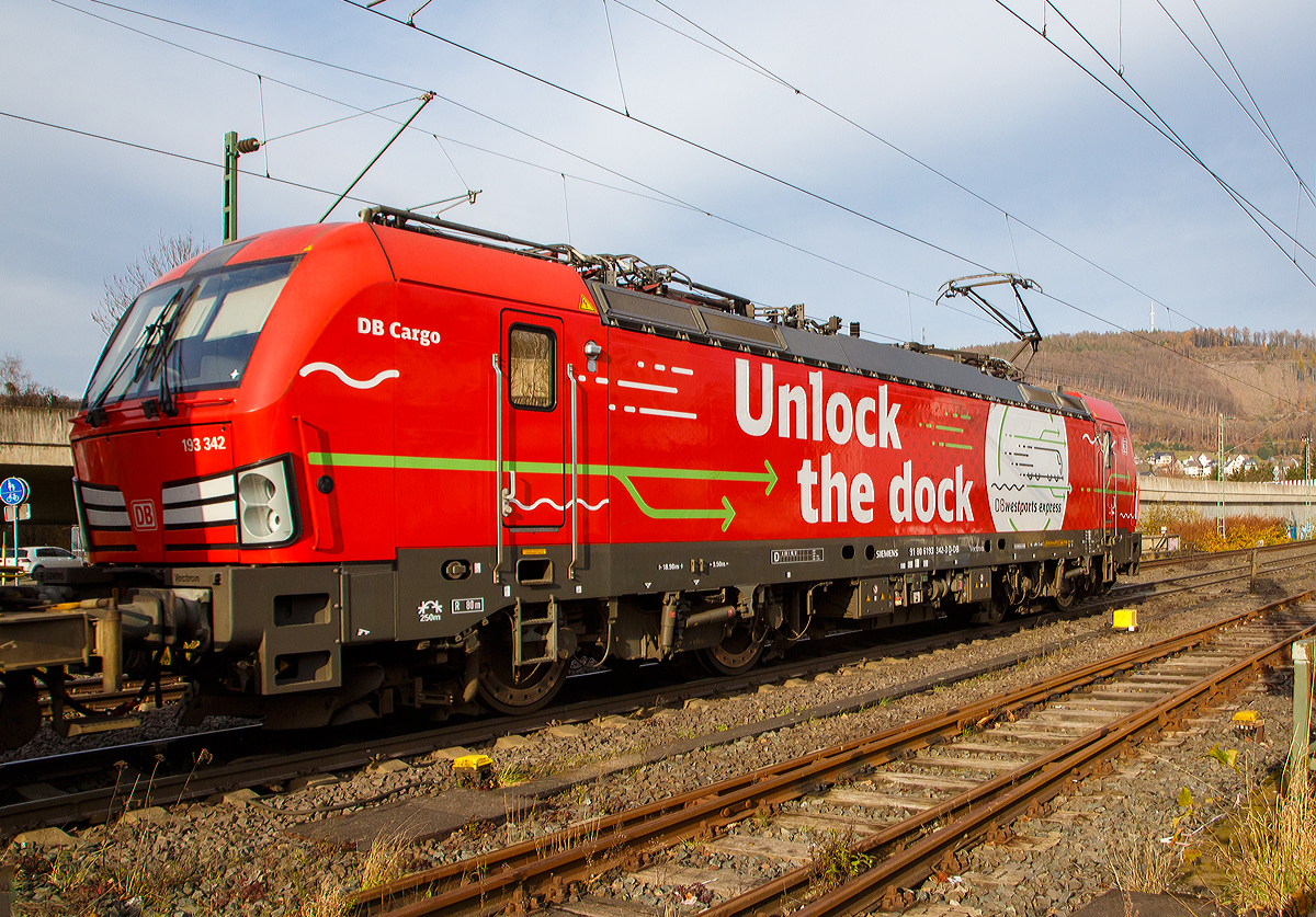 Die Siemens Vectron MS 193 342-3 „Unlock the Dock“ (91 80 6193 343-3 D-DB) der DB Cargo AG fährt am 10.11.2021 mit einem „HUPAC-Zug“ (KLV-Zug) durch Niederschelden in Richtung Siegen.

Die Vectron MS wurde 2018 von Siemens in München unter der Fabriknummer 22422 gebaut und an die DB Cargo geliefert. Diese Vectron Lokomotive ist als MS – Lokomotive (Multisystem-Variante) mit 6.400 kW konzipiert und zugelassen für Deutschland, Österreich, Schweiz, Italien, Belgien und Niederlande, sie hat eine Höchstgeschwindigkeit von 200 km/h. So ist es möglich ohne Lokwechsel vom Mittelmeer die Nordseehäfen Rotterdam oder Hamburg an zu fahren.

Die Vectron MS hat folgende Leistungen:
Unter 15kV, 16,7Hz und 25kV, 50Hz Wechselstrom mit 6.400kW;
unter 3kV Gleichstrom mit 6.000kW sowie
unter 1,5kV Gleichstrom 3.500kW

Auf dem Dach der Lok befinden sich vier Einholmstromabnehmer
Position A Pantograf für AC 1.450 mm breit (für Schweiz)
Position B Pantograf für DC 1.450 mm breit (für Italien)
Position C Pantograf für DC 1.950 mm breit (für Niederlande)
Position D Pantograf für AC 1.950 mm breit (für Deutschland, Österreich), Position D ist hier im Bild vorne.
