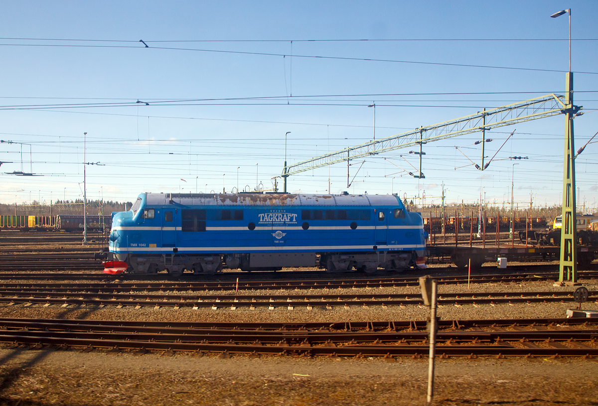 
Die Svensk Tgkraft AB (STAB) TMX 1042, ex DSB MX 1042, eine NOHAB  AA16, steht am 22.03.2019 in Nssj (Schweden). Die Aufnahme konnte ich aus einem fahrenden Zug machen.

Die NoHAB Rundnase wurde 1962 von der schwedischen Lokfabrik Nydqvist och Holm AB (NoHAB) unter der Fabriknummer 2482 gebaut und als MX 1042 an die Dnische Staatsbahn DSB (Danske Statsbaner) geliefert. Seit 1994 ist sie wieder in ihren Entstehungsland Schweden. 
Lebenslauf:
1962 bis 1994: DSB
1994 bis 1997: BSX
1997 bis 2000: BSM
2000 bis 2004: BK-Tg
2004 bis 2008: STT
2008 bis heute: Tgkraft

Dreh- und Angelpunkt der Entwicklung in Europa war der schwedische Maschinen- und Lokbauer „Nydqvist och Holm AB“ (NoHAB) in Trollhttan, der 1949 die Lizenzen zum Bau von EMD-Dieselloks erhielt. Dieser berarbeitete die Konstruktion einer an die australische Victoria Railways gelieferten Lok, wobei das engere UIC-Umgrenzungsprofil eine wesentliche Rolle spielte. Besonders das niedrige Lichtraumprofil der SNCF in Frankreich war dabei mageblich. Tatschlich wurde die AA16 vor Schnellzgen und TEE-Zgen zwischen Brssel und Paris eingesetzt.

Als erste Staatsbahn beschaffte die Dnische Staatsbahn DSB (Danske Statsbaner) Lokomotiven von NOHAB. Die ersten vier dieselelektrischen Loks wurden bereits 1952 bestellt, obwohl die Loks nur auf dem Papier existierten. Im Frhjahr 1954 erfolgte die Auslieferung von NOHAB als MY 1101 bis 1104. Die Beschaffung von Loks aus bersee war heftig umstritten und so wurde der DSB-Haus-und-Hof-Lieferant Frichs aus Aarhus in die Lieferung mit einbezogen. Frichs lieferte die Lokksten und Drehgestelle ab MY 1102 NOHAB zu. Die Loks der ersten Kleinserie erhielten den 16-Zylinder-Motor Typ GM 16-567 B, der nur eine Leistung von 1.700 PS hatte. Die MY 1101 wurde als erste NOHAB-Rundnase berhaupt am 07.02.1954 an die DSB ausgeliefert.

Die DSB Baureihe MY mit ca. 17 Tonnen Achslast konnten aber nicht auf den dnischen Nebenbahnen eingesetzt werden. Aus diesem Grund beschaffte ab 1960 die DSB 45 Loks als Baureihe MX. Diese MX-Loks bekamen 12-Zylinder-Motoren. Die erste Serie bekam den Motortyp GM 12-567 C mit 1.425 PS und die zweite den Typ GM 12-567 D1 mit 1.445 PS. Mit einem Dienstgewicht von nur noch 89 Tonnen und einer Achslast von 16 Tonnen konnten die MX auf allen DSB-Strecken eingesetzt werden.

Bei dem (General Motors) GM-Dieselmotor handelte es sich um den V12-Zylinder-Zweitakt-Dieselmotor mit Roots-Lader, ab MX 1021, vom Typ GM 12-567 D1. Dieser hat wie allen EMD 567-Motore einen Zylinderdurchmesser von 8 1/2 Zoll (216 mm) und ein Hub von 10 Zoll (254 mm), was zu einem Hubraum von 567 Kubikzoll pro Zylinder, entsprechend 9.292 cm, fhrte. Aus diesem Wert leitet sich die Bezeichnung der Baureihe ab. Mit 835 U/min und einer Verdichtung von 20:1 hat der Motor eine Leistung von 1.064 kW (1.445 PS)

Die Idee, ein 2-Takt-Diesel zu verwenden war theoretisch gut, denn ein 2-Takter erbringt (rechnerisch) bei gleichem Hubraum die doppelte Leistung eines 4-Takt-Motors, hat also groe Gewichtsvorteile und braucht weniger Platz. - In der Praxis ist dies jedoch relativ. Bauteile mssen strker dimensioniert werden, die groen Geblse (meist Rootsgeblse) und deren Antrieb sind schwer und brauchen einigen Platz. Zudem nutzt der 2-Takt-Motor den Kraftstoff schlechter aus, er  suft .  Auerdem ist ein 2-Takt-Diesel sehr laut, fast kreischend, daher auch der typische Sound dieser Lokomotiven.

TECHNISCHE DATEN:
Anzahl: 45 (fr DSB)
Hersteller: NOHAB / GM 
Spurweite: 1.435 mm (Normalspur)
Achsfolge: (Ao1Ao)' (Ao1Ao)' 	
Lnge ber Puffer : 18.900 mm 	
Hhe: 4.295 mm
Breite: 3.080 mm
Drehzapfenabstand: 10.300 mm
Achsabstand im Drehgestell:  3.400 mm
Treibraddurchmesser: 1.015 mm
Laufraddurchmesser: 950 mm
Dienstgewicht: 89 t 	
Achslast: 16 t
Motor: GM type 567D1, 12-Zylinder, Zweitakt-Dieselmotor
Hubraum: 111,50 Liter
Leistung: 1.064 kW (1.445 PS) bei 835 U/min
Tankinhalt:  2.800 l
Anzahl der Fahrmotoren: 4
Kraftbertragung: dieselelektrisch (Dieselmotor auf Generator, dieser liefert dann die elektrische Energie fr die 4 Fahrmotoren)	
Hchstgeschwindigkeit : 120 km/h 	
Kupplungstyp:  Schraubenkupplung
