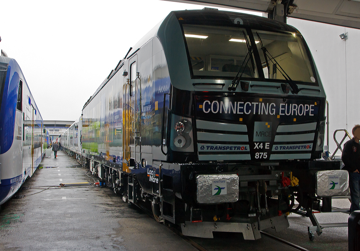 Die X4 E – 875   Anni   193 875-2  (91 80 6193 875-2 D-DISPO)  mit Werbung  Connecting Europe  der MRCE - Mitsui Rail Capital Europe GmbH, zurzeit vermietet an Transpetrol GmbH Internationale Eisenbahnspedition in Hamburg, wurde am Freigelände auf der Inno Trans 2014 in Berlin ausgestellt (hier 26.09.2014).  

Die Lok wurde 2014 von Siemens in München unter der Fabriknummer 21915 gebaut und an die MRCE geliefert. Die Vectron Lokomotive ist als AC – Lokomotive konzipiert mit 6.400 kW und zugelassen für Deutschland, Österreich und Ungarn inklusive ETCS, sie hat eine Höchstgeschwindigkeit von 200 km/h.
für Deutschland, Österreich und teilweise Ungarn, inklusive ETCS.

Technische Daten:
Spurweite: 1.435 mm
Achsformel: Bo'Bo'
Länge über Puffer: 18.980 mm
Drehzapfenabstand: 9.500 mm
Achsabstand im Drehgestell: 3.000 mm
Breite: 3.012 mm
Höhe:  4.248 mm
Raddurchmesser :  1.250 mm (neu) / 1.170 mm (abgenutzt)
Gewicht:  87 t
Spannungssysteme: 15 kV, 16,7 Hz und 25 kV, 50 Hz AC
Max. Leistung am Rad:  6.400 kW
Höchstgeschwindigkeit: 200 km/h
Anfahrzugskraft:  300 kN
Dauerzugkraft:  250 kN
Elektrische Bremskraft: 150 kN
Kraftübertragung: Ritzelhohlwellenantrieb
Lichtraumprofil: UIC 505-1