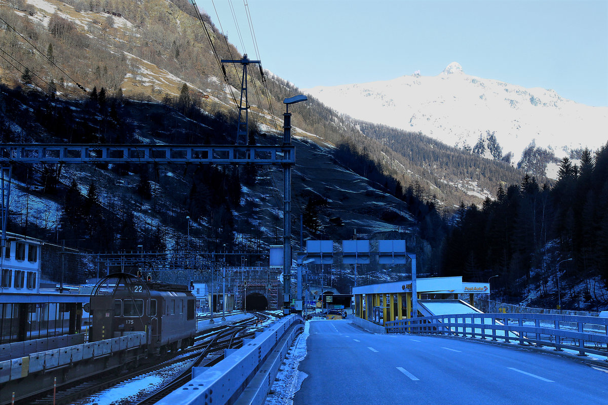 Ein eisiger Morgen in Goppenstein: Ausfahrt der BLS Re 4/4 175 mit ihrem Autozug Richtung Lötschberg Tunneleingang. Langsam tastet sich die wärmende Sonne den Hang herab. 7.Januar 2021