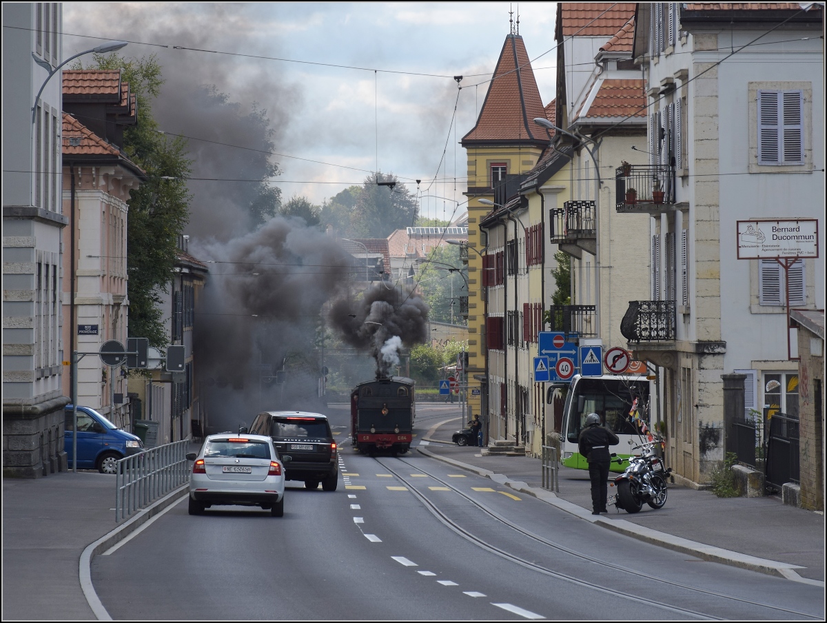 Eine etwas ungewöhnliche Verkehrsteilnehmerin in La Chaux-de-Fonds. 

Um die Kurve gefahren und schon rette sich, wer kann. Denn CP E 164, heute bei La Traction, schnaubt mit viel Rauch als Geisterfahrerin die Rue du Manège hinauf. So sammeln sich respektvoll immer mehr Autofahrer auf der falschen Strassenseite. September 2021.