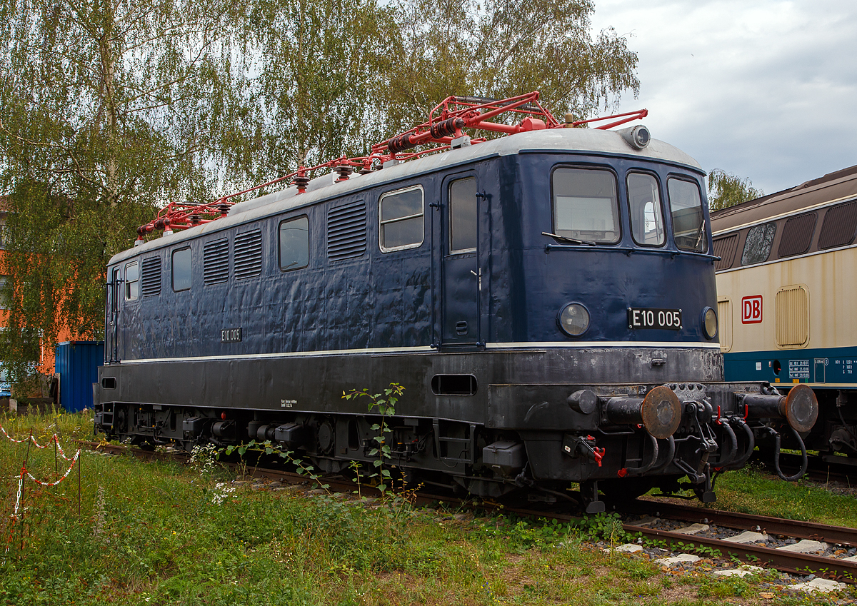 Eine ungewohnte E 10:
Die E 10 005, später 110 005–6, steht am 04.09.2020 im DB Museum Koblenz-Lützel. Diese fünfte Vorserien E 10 wurde 1953 von Henschel & Sohn in Kassel unter der Fabriknummer 28467 gebaut, die Elektrik wurde von AEG unter der Fabriknummer 7174 geliefert.  Zum 30.08.1979, nach einer Laufleistung von 4,34 Mio. km, erfolgte die Ausmusterung bei der DB und 1980 wurde sie zur Museumslok.

Die Vorserienlokomotiven wurden weitgehend von der Industrie entwickelt, wobei verschiedene Komponenten ausprobiert wurden:
Die E 10 001 stammt im mechanischen Teil von Krauss-Maffei und im elektrischen Teil von AEG. Sie besaß einen Alsthom-Gelenkhebelantrieb.
Die E 10 002 stammt mechanisch von Krupp und elektrisch von BBC und hatte einen BBC-Scheibenantrieb.
Die E 10 003 kam von Henschel und SSW und hatte einen SSW-Gummiringfederantrieb.
Die E 10 004 lieferten Henschel und AEG und sie wurde durch einen Sécheron-Lamellenantrieb angetrieben. Baugleich mit ihr war die E 10 005, die 1953 nachgeliefert wurde, um die Lokomotiven auch im täglichen Betrieb testen zu können.

Die neuen Lokomotiven sollten Schnellzüge mit 700 t auf 10 ‰ mit 90 km/h und Güterzüge mit 1300 t auf 5 ‰ mit 70 km/h befördern können. Die Höchstgeschwindigkeit war mit 125 km/h angesetzt. Eine Zugkraft von 7 t am Radumfang war gefordert, wobei 6 t bereits 5 Sekunden nach dem Anfahren aus dem Stillstand erreicht werden mussten. Die Erwärmung der Fahrmotoren durfte 90 Grad nicht überschreiten. Auch durften Schwankungen bei der Fahrdrahtspannung zwischen 10,5 und 18,5 kV keine Betriebsstörungen verursachen. Die Loks sollten zweiachsige Drehgestelle mit Drehzapfen erhalten, wobei die Zugkraftübertragung über den Brückenrahmen und nicht mehr über die Drehgestelle (wie bei der E 44) erfolgen sollte. Auf Vorbauten, wie sie bei den Vorkriegselloks aus Sicherheitsgründen zu finden waren, glaubte man verzichten zu können. Schließlich war Vielfachsteuerung für den Einsatz in Doppeltraktion sowie die Ausrüstung für den Wendezugeinsatz einzubauen. 

Gegenüber den Vorplanungen wurde die Höchstgeschwindigkeit auf 130 km/h heraufgesetzt und die Baureihenbezeichnung in E 10 umgewandelt. Entsprechend dem Schweizer Vorbild waren es Drehgestell-Lokomotiven mit einzeln angetriebenen Achsen jedoch mit unterschiedlichen Antrieben.

Die Auslieferung der Loks erfolgte im Zeitraum zwischen dem 23. August 1952 (E 10 001) und dem 23. März 1953 (E 10 005).

Die E 10-VorserienIoks sollten dazu dienen, möglichst viele neue Bauteile auf ihre Verwendbarkeit für die künftigen Serienloks zu testen. Deshalb unterschieden sie sich weitgehend voneinander und von den folgenden Serienloks.
Einige Bauteile waren jedoch im Prinzip gleich aufgebaut und nur in der Ausführung etwas verschieden. Dazu gehörte der Brückenrahmen, der bei allen Loks aus kastenförmig zusammengeschweißten Stahlblechen bestand. Er setzte sich jeweils aus zwei Längsträgern, zwei Kopfstücken, drei Querträgern (für die Drehzapfen und den Trafo) sowie Deckblechen zusammen und musste die Zug- und Stoßkräfte aufnehmen.
Auch der Kastenaufbau war bei allen Vorserienloks ähnlich konstruiert. Er bestand jeweils aus einem selbsttragenden Gerippe von Stahlprofilen, die auf den Brückenrahmen geschweißt waren und durch angeschweißte Mantelbleche verkleidet wurden. 

Die fünf Vorserien-Lokomotiven der Baureihe E 10.0 wurden zwischen 1975 und 1979 ausgemustert. Erhalten sind die Museumslokomotiven E 10 002 und E 10 005.

TECHNISCHE DATEN der E10 004 und 005:
Spurweite: 1.435 mm
Achsanordnung:   Bo´Bo´   
Länge über Puffer:  15.900 mm 
Treibraddurchmesser: 1.250 mm (neu)
Dienstgewicht:  80 t   
Achslast: 20 t   
Höchstgeschwindigkeit :  130 Km/h
Anfahrzugkraft: 255 kN
Dauerzugkraft: 118 kN
Nennleistung:  3.440 kW
Anzahl Fahrmotoren  4   
Stromsystem:  Einphasen-Wechselstrom 15 000 V, 16 2/3 Hz 