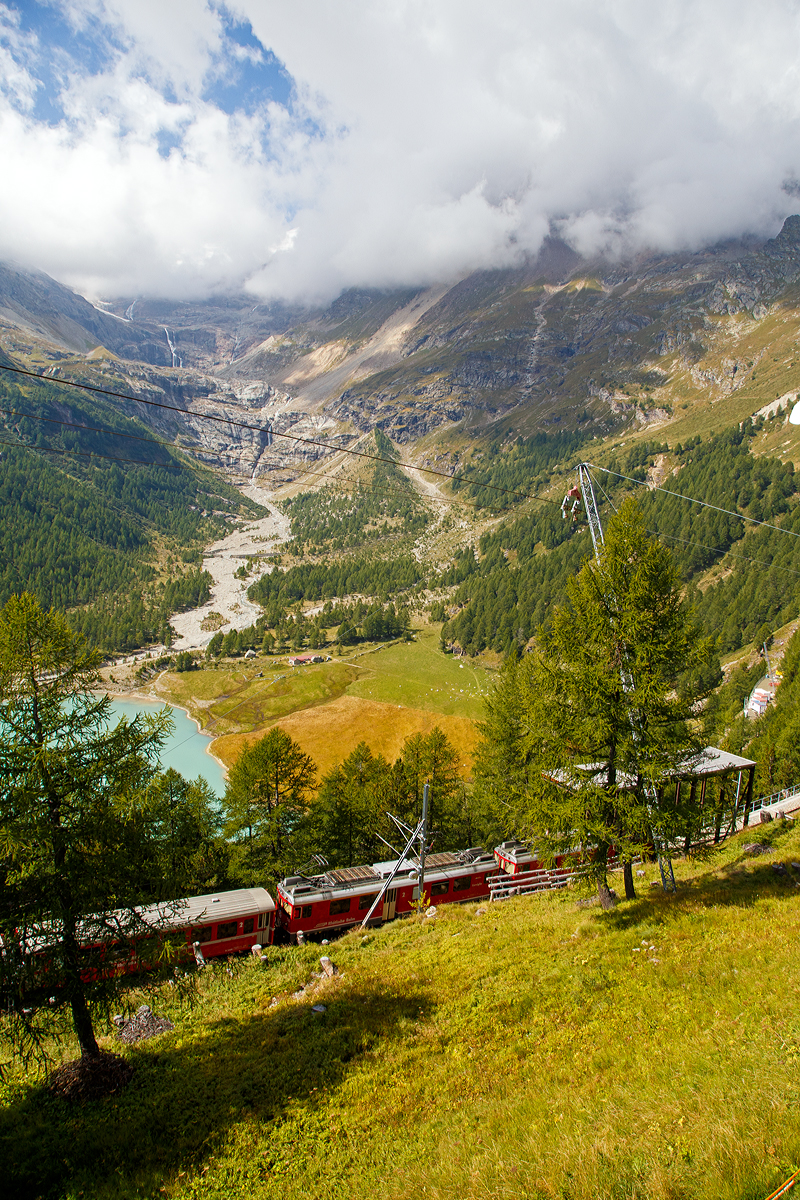 Geführt von den beiden RhB ABe 4/4 III Triebwagen 54  Hakone  und  56  Corviglia  fährt der RhB-Regionalzug nach Tirano am 06.09.2021 von Alp Grüm hinab ins Puschlav.

Unten der Lago Palü (Lagh da Palü, dt. Palüsee) am Fuße des Piz Palü. Der See wird größtenteils vom Palügletscher gespeist.