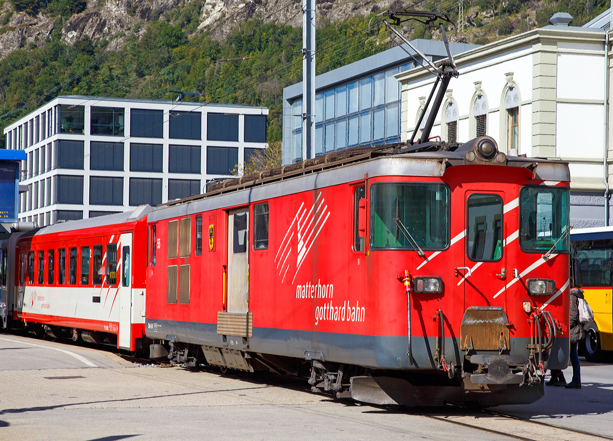 Geschoben von dem elektrischen Zahnradtriebwagen Deh 4 /4 – 55 „Brig“ erreicht der MGB Regionalzug von Andermatt am 16.09.2017 den Bahnhof Brig.

Der Gepäcktriebwagen wurde 1972 gebaut, der Lokomotivkasten ist von SIG, die Triebdrehgestelle von SLM und die elektrische Ausrüstung von BBC.

Da das Rollmaterial in den 60er Jahren großenteils veraltet und der Verkehr in der Wintersaison stark angestiegen war, benötigte die FO dringend leistungsfähigere Triebfahrzeuge. Man entschied sich für leistungsfähige Gepäcktriebwagen, die freizügig auf dem gesamten Netz eingesetzt werden konnten. Die fünf Fahrzeuge des Typs Deh 4/4 wurden 1972 bestellt und lösten die HGe 2/2 und die ABDeh 2/4 ab, die den Wintersportverkehr auf der Schöllenenbahn nicht mehr bewältigen konnten. 

Ein Nachbau der FO-Deh 4/4 erhielt einen völlig andersartigen Kasten, weshalb diese Fahrzeuge bei der FO als Deh 4/4 I und II unterschieden wurden. Seit der Fusion zur MGB ist diese Bezeichnung nicht mehr gebräuchlich, die MGB unterscheidet die Serien nach den Nummernbereichen 21, 51 und 91. Wobei sie sich schon optisch und auch technisch etwas unterscheiden.

Technische Daten Deh4/4 I (51-55):
Spurweite: 1.000 mm
Achsformel: Bo'zz Bo'zz
Länge über Puffer: 16.900 mm
Größte Breite: 2.650 mm
Größte Höhe (bei abgesenkten Stromabnehmer): 3.880 mm
Leergewicht: 48,3  t 
Dienstgewicht: 50,3 t
Maximale Zuladung: 2,0 t
Höchstgeschwindigkeit: Adhäsion 60 km/h / Zahnstange 30 km/h
Stundenleistung: 1.032 kW
Dauerleistung: 936 kW
Treibraddurchmesser: 	790 mm (Adhäsion) / 688 mm (Zahnrad)
Stromsystem: 11 kV 16,7 Hz AC
Anzahl der Fahrmotoren: 4
Größe der Ladefläche: 11,5 m2
