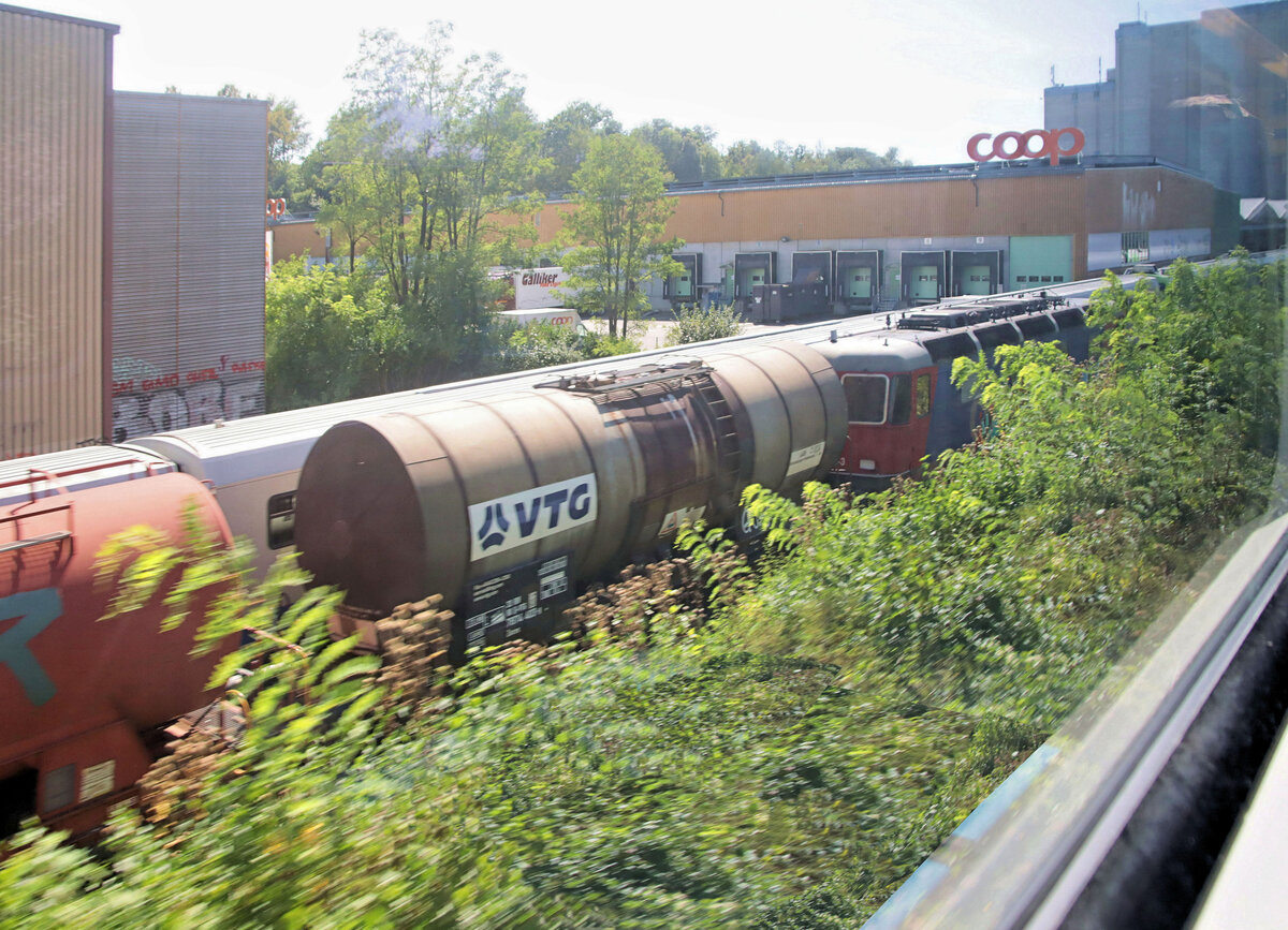 Hastiges Bild im Vorbeifahren an der langen Reihe von Fahrzeugen, die in Kaiseraugst auf Abbruch warten. Erkennbar auch eine Re 6/6, vermutlich 620 046. Neben Güterwagen wartet eine grosse Zahl BLS-Fahrzeuge auf Abbruch (NPZ Trieb- und Steuerwagen, Steuerwagen der Autozüge Lötschbergtunnel, BLS Lok Re 4/4 179, und Triebzüge der Centovallibahn). 21.August 2024 