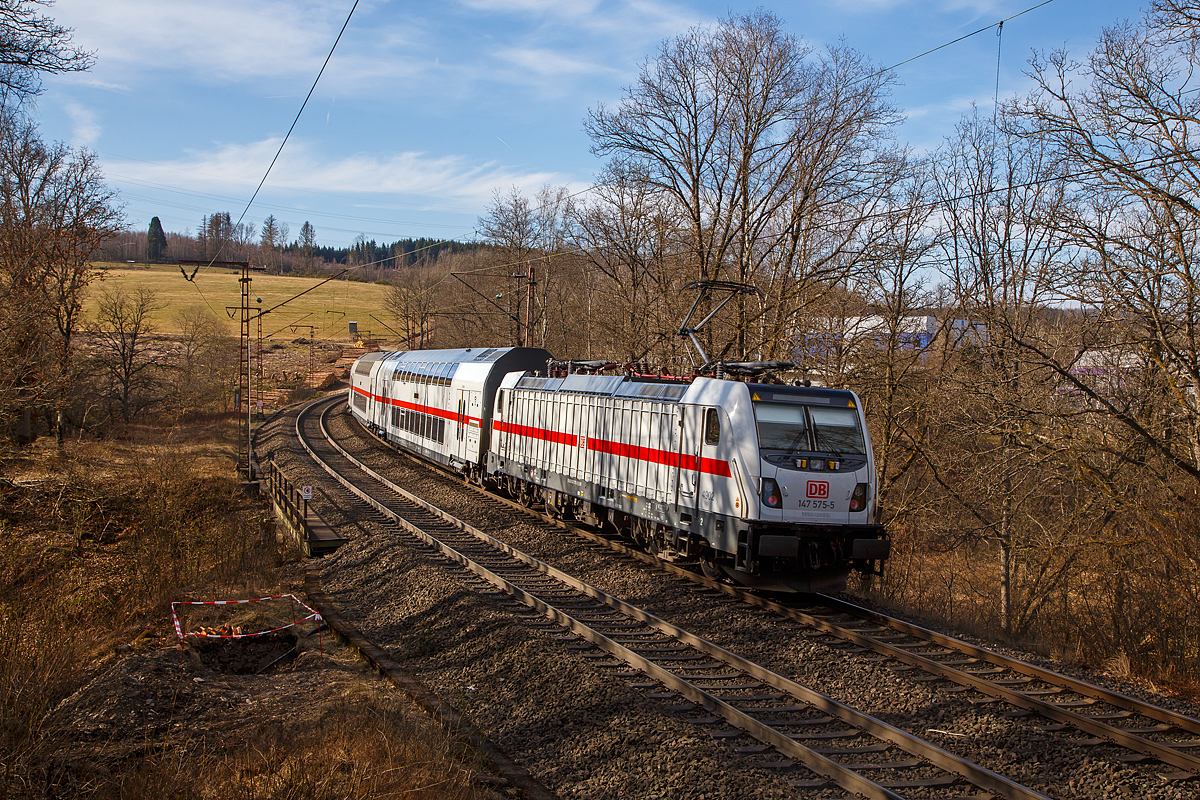 Hier nun als Nachschuss.....
Die 147 575-5 (91 80 6147 575-1 D-DB – IC 4902) schiebt den IC2, am 13.03.2022, als IC 2228 / RE 34 (Frankfurt a.M. Hbf - Siegen – Hamm/Westf. Hbf), durch Wilnsdorf-Ruderdorf in Richtung Siegen.

Die TRAXX P160 AC3 wurde 2019 von Bombardier in Kassel unter der Fabriknummer KAS 35619 gebaut und an die DB Fernverkehr AG geliefert. Sie hat die Zulassungen für Deutschland. Für die Schweiz ist die Zulassung auch vorgesehen, daher hat sie auch vier Stromabnehmer, doch wurde noch keine Zulassung durch die Schweiz vom Hersteller erlangt.
