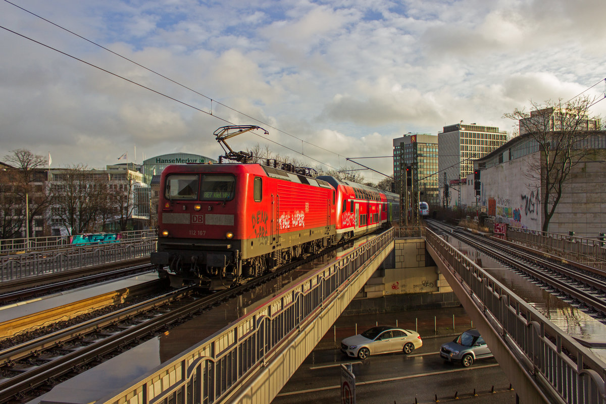 Im Streiflicht der tiefstehenden Sonne fahren am 04.01.2018 112 167 und 112 171 am Zugschluss mit einem RE7 nach Kiel in Hamburg Dammtor ein.