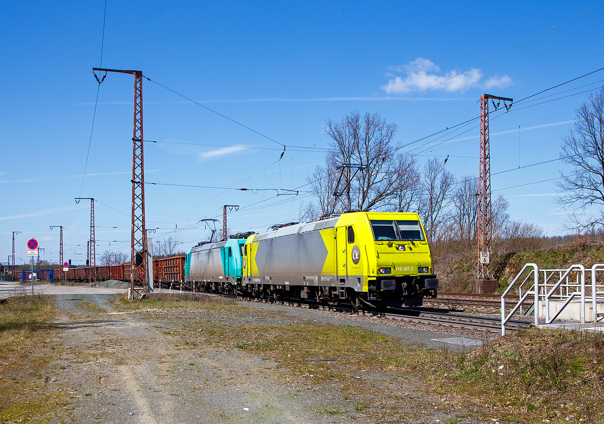 In Doppeltraktion fahren die 119 007-2 (91 76 0119 007-2 N-RHC), ex 185 626-9, und die 185 577-4 (91 80 6185 577-4 D-BEBRA), beide sind TRAXX F140 AC2-Mietloks der Alpha Trains, am 22.04.2021 mit einem offenen Gterzug durch Rudersdorf (Kreis Siegen) in sdlicher Richtung. 

Vorne die 119 007-2 wurde 2009 von Bombardier in Kassel unter der Fabriknummer 34656 gebaut und als 185 626-9 geliefert. Sie wurde von 2009 bis 2014 nach Norwegen an CargoNet AS vermietet und wurde so auch in Norwegen als 91 76 0119 007-2 N-CN registriert. Sie kam dann wieder nach Deutschland blieb aber in Norwegen registriert (die derzeitige Halterkennung ist mir ungewiss). Sie hat die Zulassungen fr  Deutschland, sterreich, Schweden und Norwegen (D/A/S/N).

Dahinter die 185 577-4 wurde 2006 von Bombardier in Kassel unter der Fabriknummer 34139 gebaut. Sie hat die Zulassungen fr  Deutschland, sterreich und die Schweiz (D/A/CH).

Beide Bombardier TRAXX F140 AC2 sind aktuell an die HLG - Holzlogistik und Gterbahn GmbH (Bebra) vermietet.

Die TRAXX 2 ist eine Weiterentwicklung der Traxx-Baureihen, gegenber welchen sie als augenflligste nderung einen berarbeiteten Lokkasten besitzt. Die nderung erfolgte um den neuen, strengeren Sicherheitsnormen bezglich Crashfestigkeit zu gengen und ist an leicht nach unten gezogenen Ecken am Lokkasten und den Frontklappen zum Ausbau der Klimaanlage zu erkennen. Gendert wurde auch die Umrichteranlage. 

Technische Daten der BR 185.2 (TRAXX F140 AC2):
Spurweite: 1.435 mm
Achsformel:  Bo’Bo’
Lnge ber Puffer:  18.900 mm
Drehzapfenabstand:  10.400 mm
Dienstgewicht: 85 t
Radsatzfahrmasse:  21,3 t
Hchstgeschwindigkeit:  140 km/h
Anzahl der Fahrmotoren:  4
Dauerleistung:  5.600 kW
Anfahrzugkraft:  300 kN
Stromsystem:  15 kV 16,7 Hz~ und 25 kV 50 Hz~
Antrieb:  Tatzlager