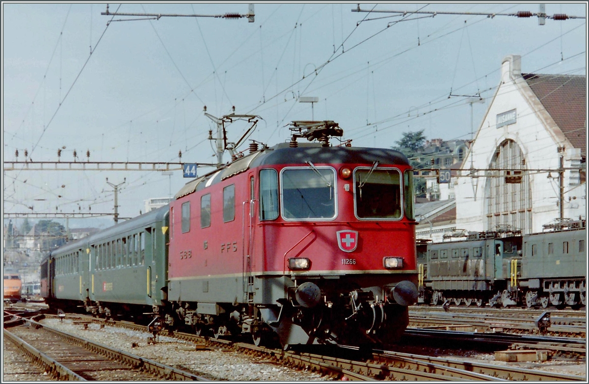 Lange Zeit bewährter Alltagsverkehr: Re 4/4 II 11266 mit EW I bzw. EW II im Schnellzugsverkehr. 
Hier erreicht die Re 4/4 II mit einem Schnellzug den Bahnhof Lausanne. 
Leider nur angescchnitten ist links noch ein TGV zu erkennen und rechts zwei mal zwei Ae 4//, die auf ihren abendlichen Güterzugseinsatz warten.
(Gescanntes Foto)
März 1994