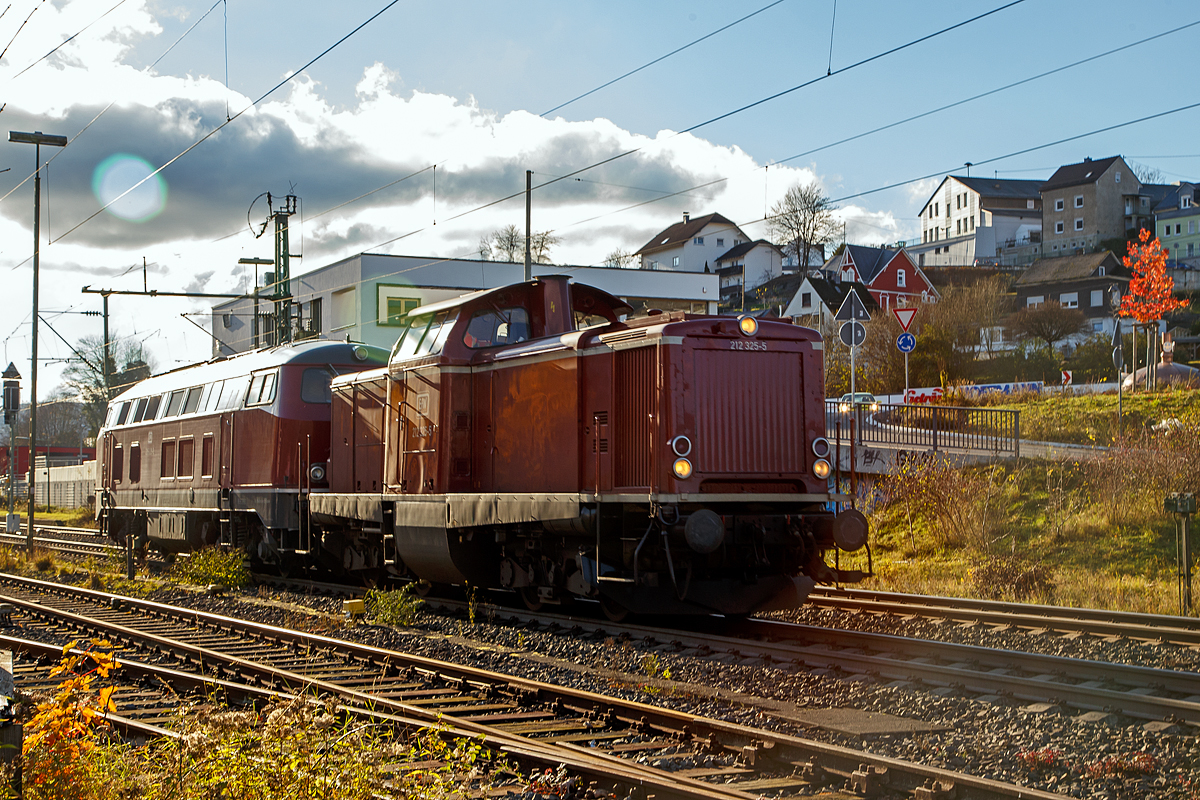Leider im starken Gegenlicht....
Die 212 325-5 (92 80 1212 325-5 D-EFW), ex DB V 100 2325, mit der 215 023-3 eigentlich 225 023-1 (92 80 1225 023-1 D-EFW) im Schlepp als Lz (Lokzug) am 22.11.2021 durch Niederschelden in Richtung Siegen. Beide Loks gehören der EfW-Verkehrsgesellschaft mbH. 

Die V 100.20 (212 325-5) wurde 1966 MaK in Kiel unter der Fabriknummer 1000372 gebaut und als V 100 2325 an die Deutsche Bundesbahn geliefert. Zum 01.01.1968 Umzeichnung in DB 212 325-5. Z-Stellung und Ausmusterung bei der DB im Jahr 2001. Im Jahr 2002 über ALS - ALSTOM Lokomotiven Service GmbH in Stendal an die EBM Cargo GmbH & Co. KG dann 2005 an TSD - Transport-Schienen-Dienst GmbH, teilweise als Mietlok. Seit 2010 ist sie nun auch bei der EfW-Verkehrsgesellschaft mbH.

Die V 163 (225 023-1) wurde 1970 bei Krupp in Essen unter der Fabriknummer 5044 gebaut an die DB geliefert. Im Jahr 2001 erfolgte der Umbau und Umzeichnung in DB 225 023-1. Seit 2013 ist sie bei der EFW. Sie ist für Steilstrecken zugelassen und besitzt zusätzlich die belgische Zugsicherung.