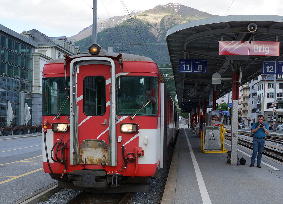 MGB: Bahnhof Brig mit Regionalzügen von Zermatt und nach Visp am späten Abend des 19. Juni 2016. Daniel Widmer von IG Schiene Schweiz wartete mit voller Konzentration auf die Ausfahrt des Regionalzuges nach Visp mit dem Deh 4/4 I 54 am Zugsschluss.
Foto: Walter Ruetsch