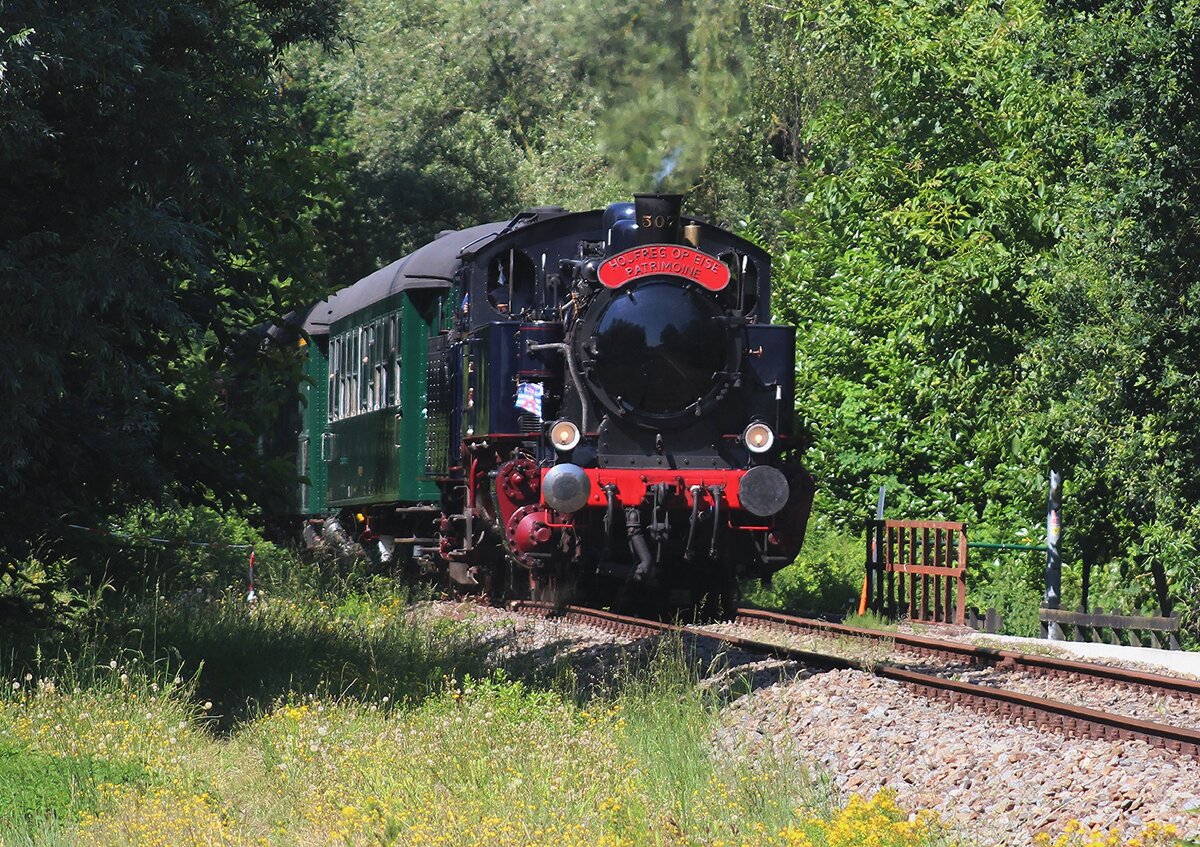 Mit etwas Zooming wird am 4 Juli 2026 bei Puurs von F�sspfad der Einfahrt von Train 1900/AMTF 507 'ENERGIE  mit der Pendelzug fotografiert. W�hrend das Spektakel  Scheldeland in Stoom  (Scheldeland unter Dampf) gibt es jede St�nde ein Museumszug zwischen Puurs und Baasrode Noord. Neben die eigene Dampfloks und Dieselloks der SDP (Stoomtrein Dendermonde-Puurs -und nicht Purs) kommen auch jedes Jahr Gastloks dazu, wie diese ex-CFL Lok von Preussische Bau uns sehen lasst. Wer belgische Dampfloks und Dieselloks liebt, soll sich unbedingt das 1. volles Wochenende von Juli in die Agenda schreiben, weil dann findet das  Schedeland in Stoom   statt.