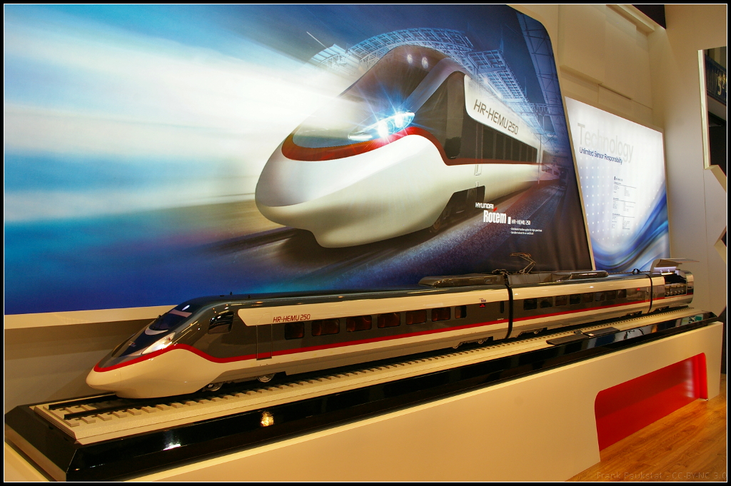 Model of Highspeed train HR-HEMU 250 for South Korea.

Auf dem Messestand von Hyundai Rotem war das Modell des neuen Hochgeschwindigkeitszugs HR-HEMU 250 ausgestellt. Der Zug erreicht eine Höchstgeschwindigkeit von 275 km/h und wird als 6-Wagen- bzw 8-Wagen-Variante ausgeliefert. Das Modell war auf der InnoTrans 2014 in Berlin zu sehen.

Daten: Länge 149 m (6-Wagen) / 198 m (8 Wagen), Kapazität 381 Fahrgäste (6 Wagen) / 533 Fahrgäste (8 Wagen),

Eingesetzt sollen die Züge auf den Strecken Seoul-Gangneung, Seoul-Bujueon, Daegok-Iksan, Pohan-Bujeon, Gwangyang-Bujeon, Suseo-Mungyeong.
