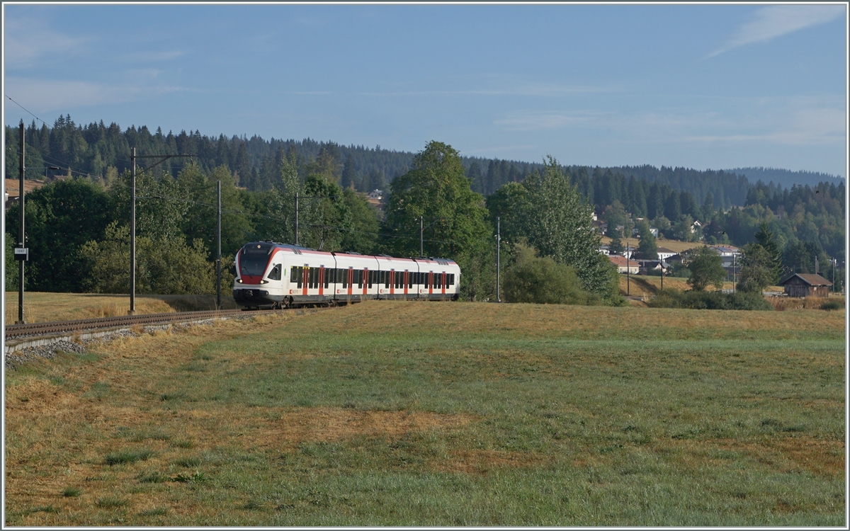 Nun haben auch wir unsere  Drei-Seen-Bahn : Die RER VAUD S2 von Aigle nach Le Brassus verbindet nicht nur recht kontrastreiche Landschaften, sie führt auch an drei Seen entlang: dem Lac Léman, dem Lac de Brent und dem Lac de Joux. A propos Wasser: Während der Genfersee durch die Rhone ins Mittelmeer mündet, entwässert sich die Orbe in die Nordsee doch der wenige Kilometer westlich von hier entspringende Doubs hingegen ins Mittelmeer.
Ganz rechts im Bild ist der von Peter schon 1967 fotografierte Schuppen zu erkennen. Zum Motiv selbst: Das Bild zeigt den SBB RABe 523 022-7 (RABe 523 94 85 0 523 022-7 CH-SBB) als S2 24216 von Aigle kurz vor der Ankunft in Le Brassus. 

15. August 2022