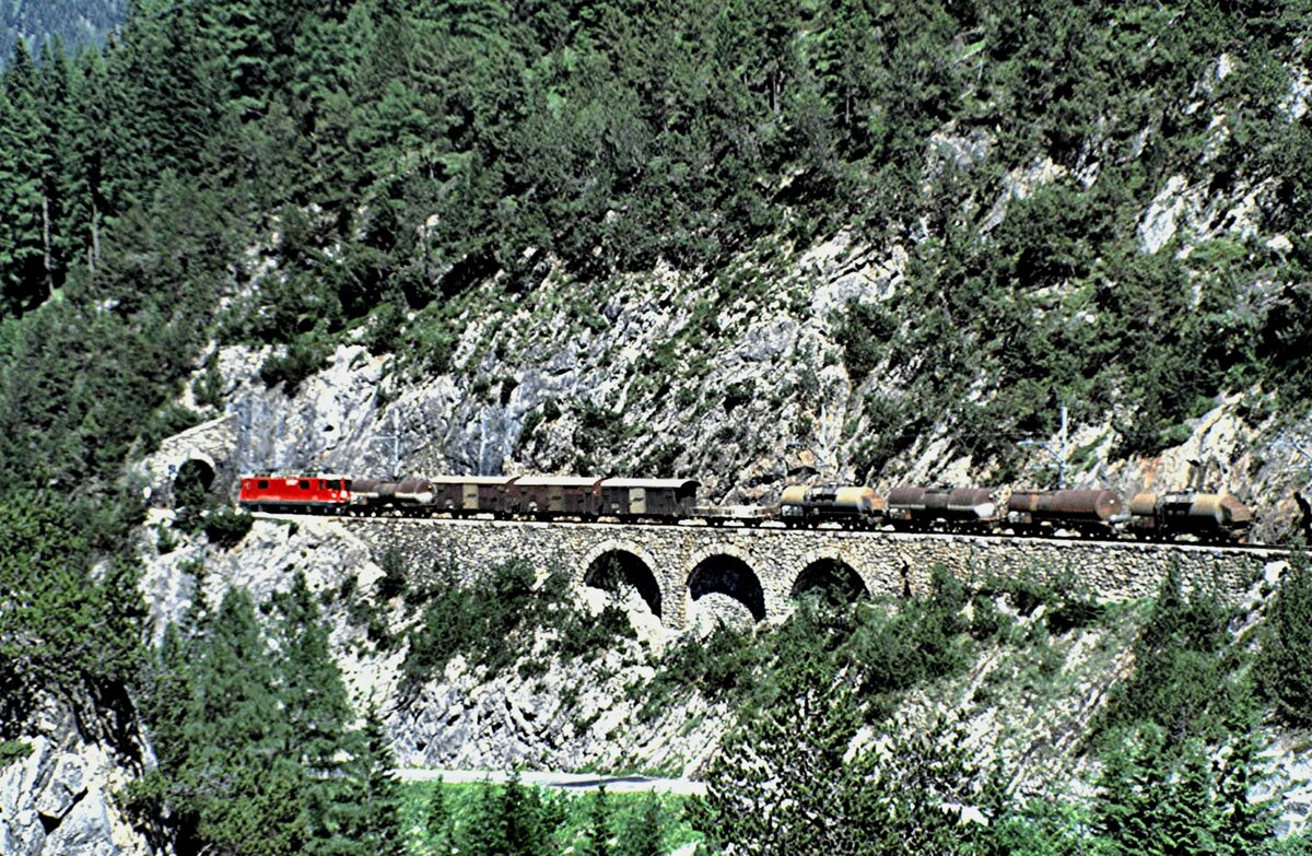 RhB Ge 4/4 II Nr.627 mit Güterzug auf dem Lehnenviadukt vor dem Fuegnatunnel auf der Albulastrecke im August 1989.