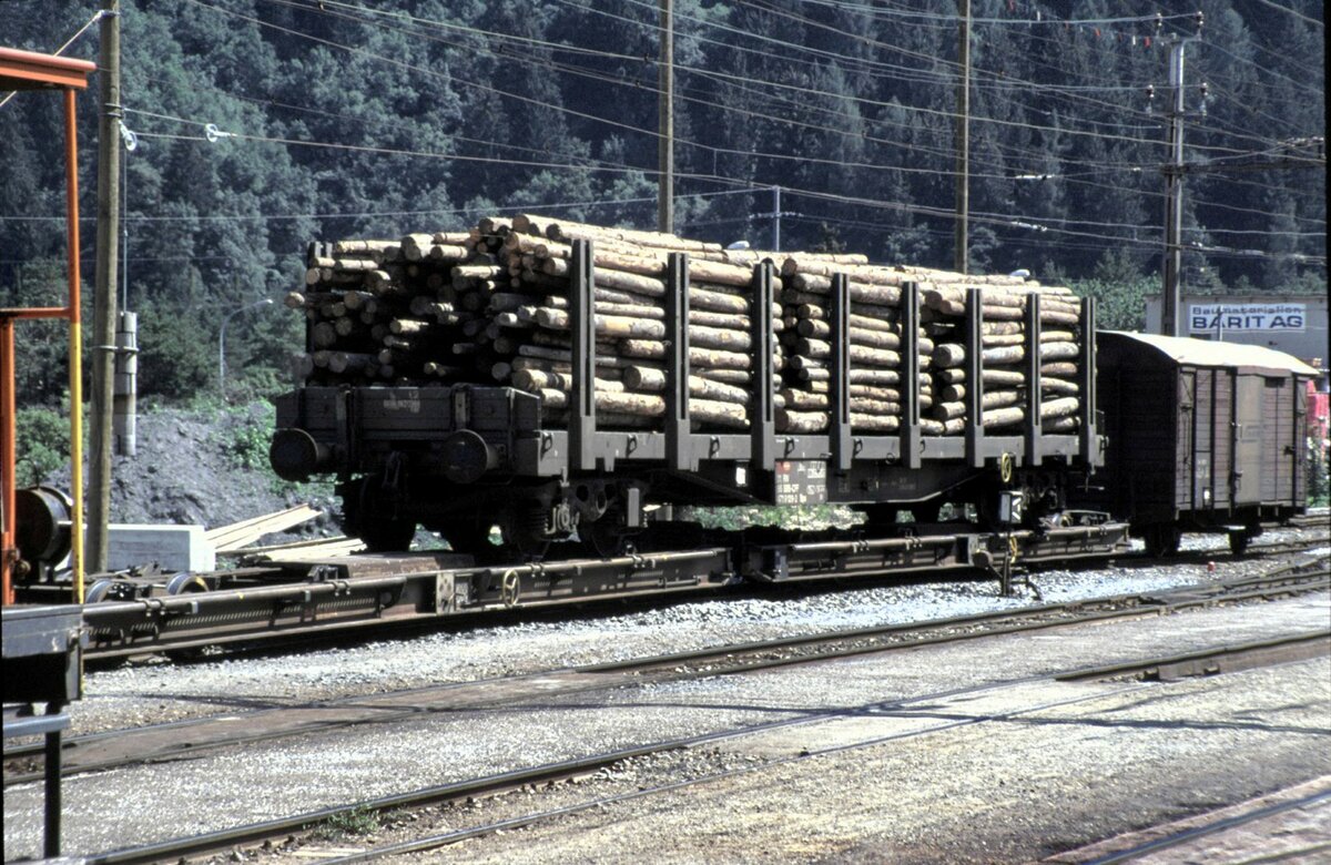 SBB Normalspur Rungenwagen 4-achsig mit Holz beladen auf RhB Rollbühne in Thusis im Oktober 1991.