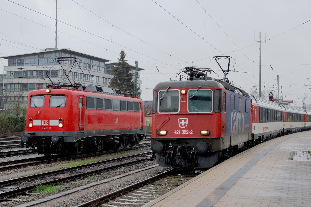 SBB/DB: Fotografieren in Singen am 20. November 2015 trotz starkem Wind und Dauerregen. Eher seltene Begegnung zwischen der 115 261-0 und der Re 421 392-2 von SBB CARGO im IC-Verkehr in Singen.
Foto: Walter Ruetsch 