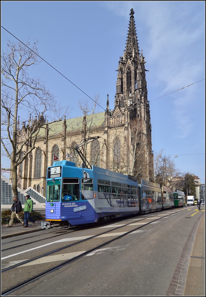 Straßenbahn Basel an der Elisabethenkirche. Entgegen kommt ein Wagen von Schindler aus den 90ern mit nachträglich eingehängtem Niederflur Mittelteil, Spitzname Guggumere. Februar 2014.