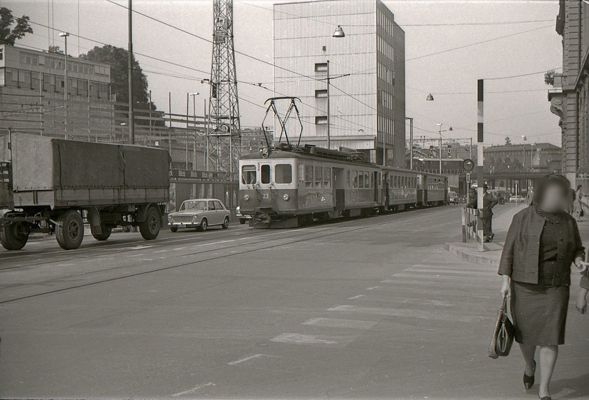 SZB Pendelzug mit Triebwagen 23 und in der Mitte vermutlich ein ehemaliger deutscher Wagen am Bollwerk. Hier gibt es längst keine Schienen mehr, nachdem zuerst die Tramlinie 1 eingestellt wurde und ein paar Wochen später die SZB (heute RBS) in den unterirdischen Bahnhof eingeführt wurde. Ueber die Bahnbrücke fährt ein offenbar ganz neuer RBe4/4 Triebwagen der SBB. 21.September 1965 